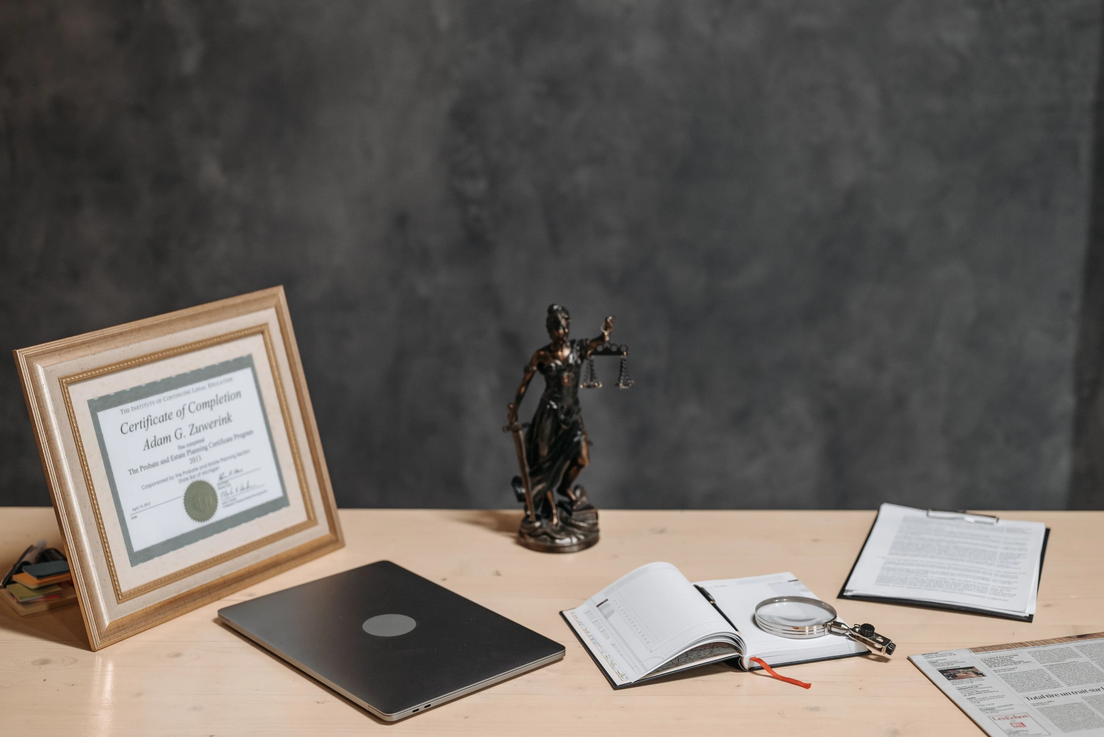 A desk with a justice figurine, diploma and documents, evoking high-stakes work where manual transcription wins