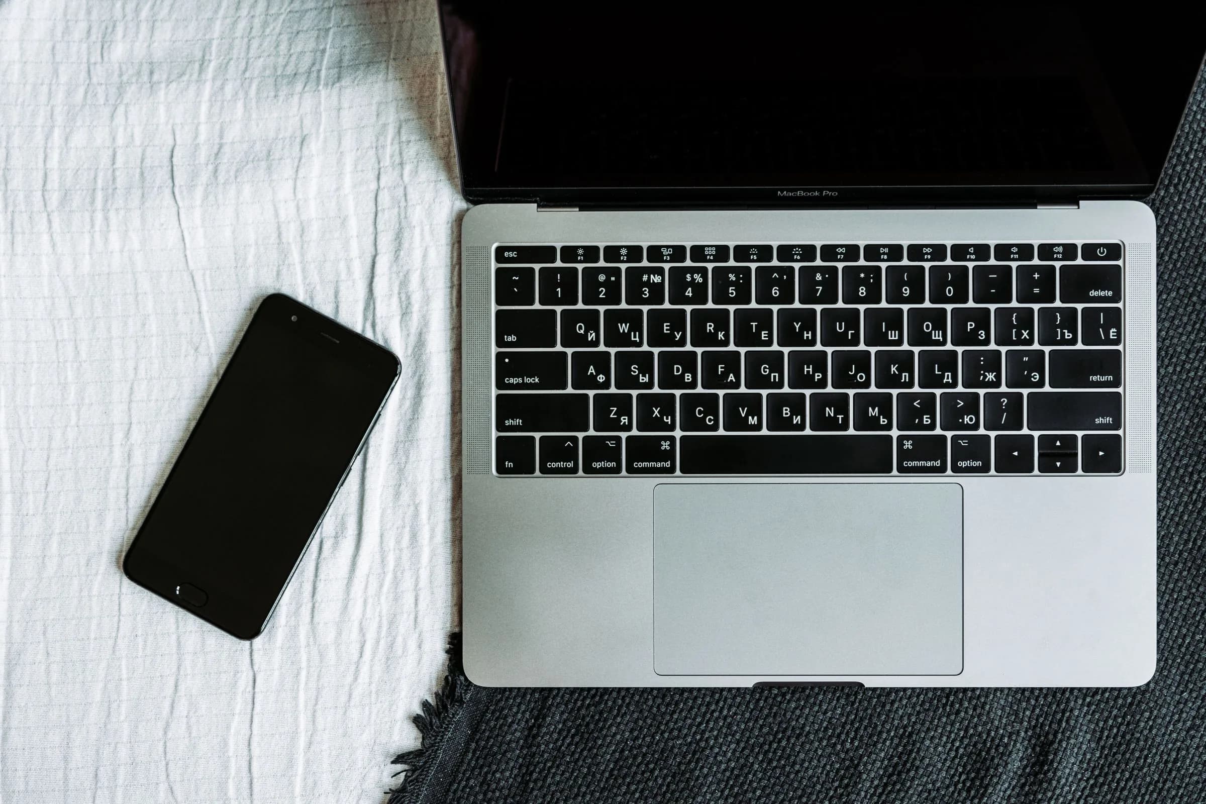 Laptop and smartphone arranged side by side on a textured surface, illustrating different devices for different note jobs