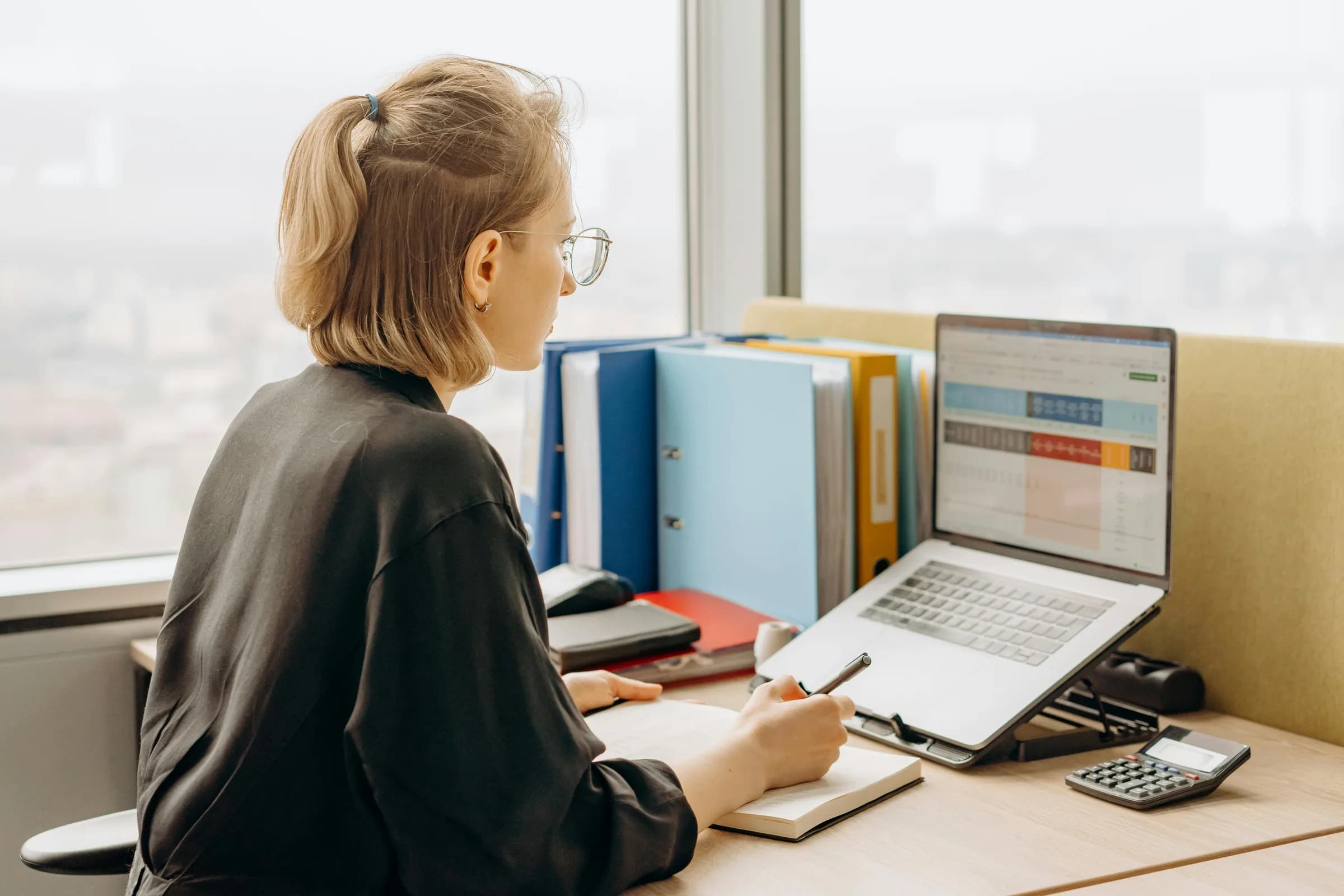 Person working at a laptop with spreadsheets open in a bright office, ready to enter data by voice