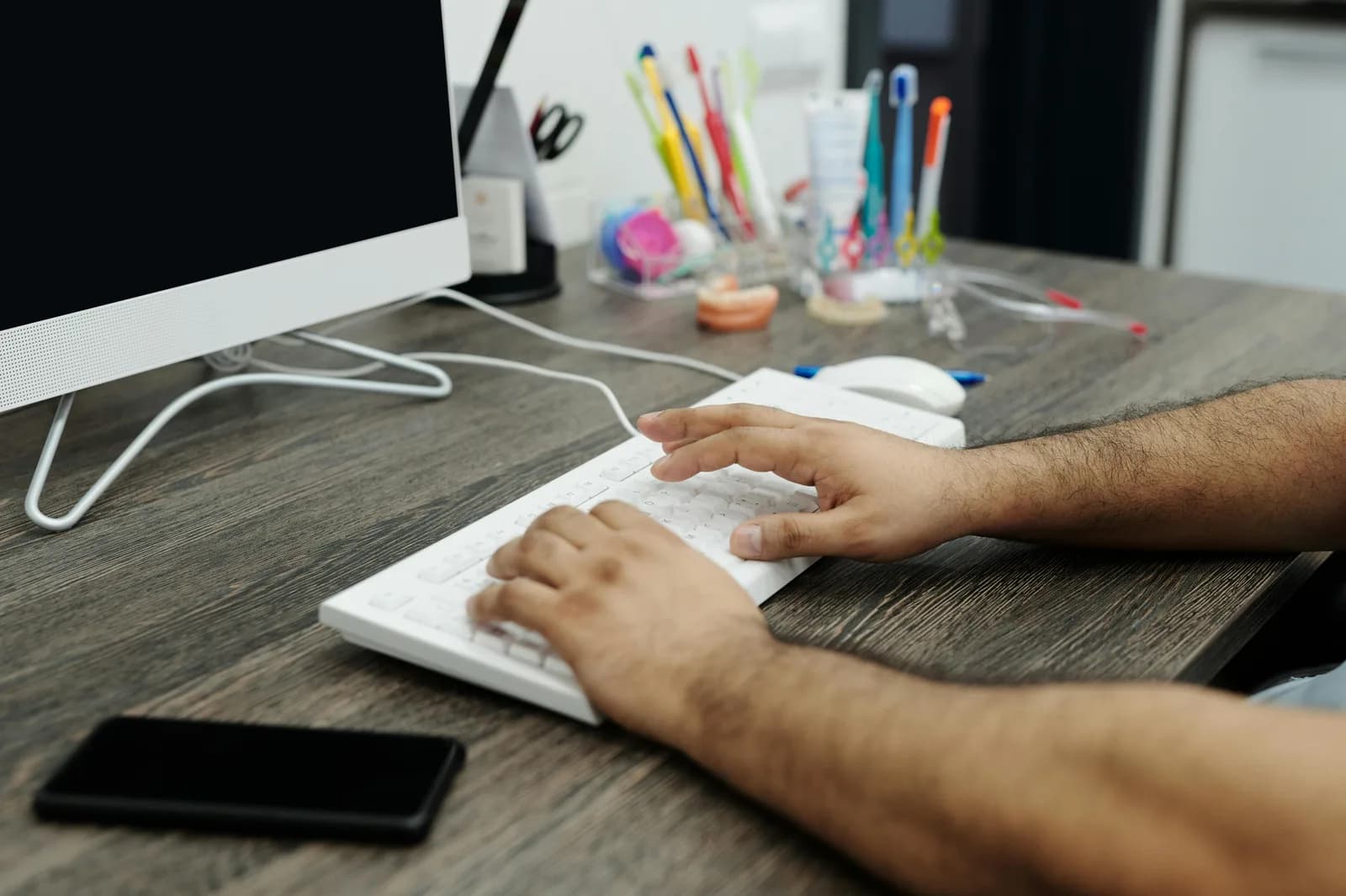 Hands typing on a keyboard at a desk, illustrating manual copy-paste work