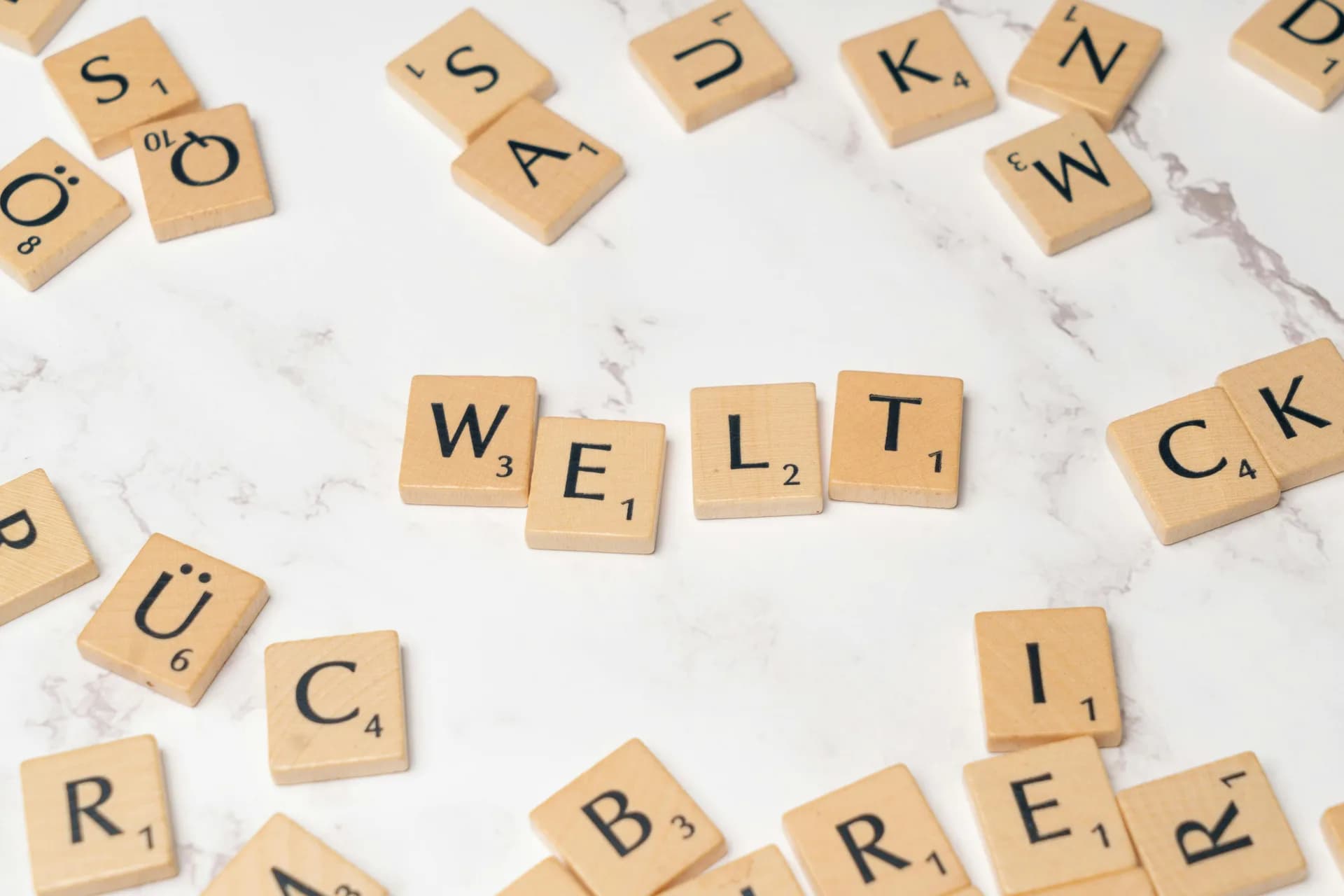 Scattered wooden letter tiles on a marble surface, evoking language and dictation that stays stuck