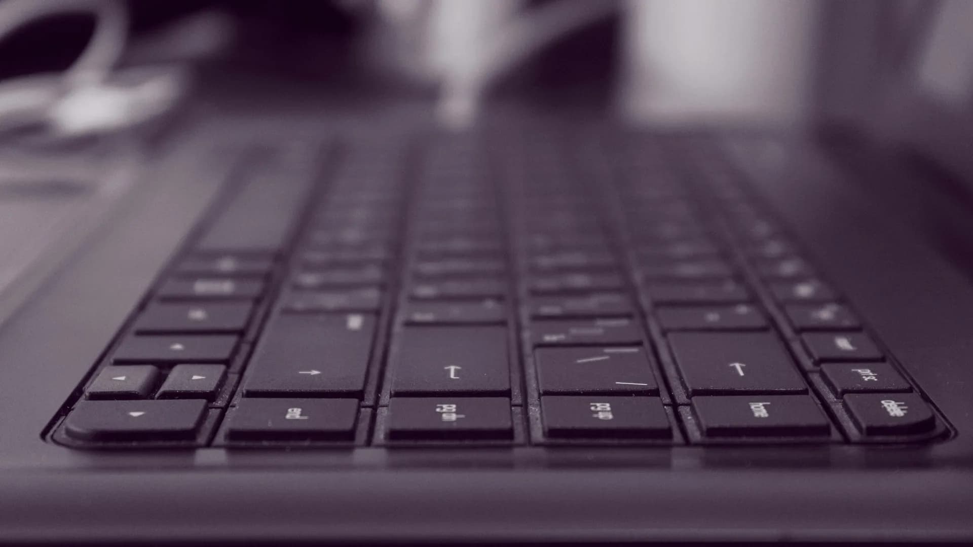 Black keyboard in shallow focus on a dark surface, evoking dictation output going onto the page