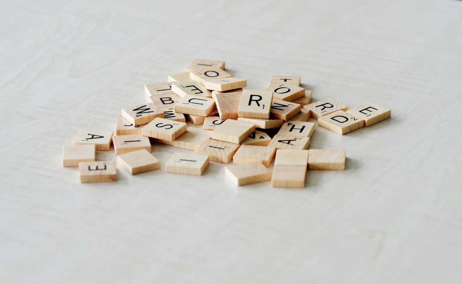 Wooden letter tiles scattered on a light table, suggesting words and language choices