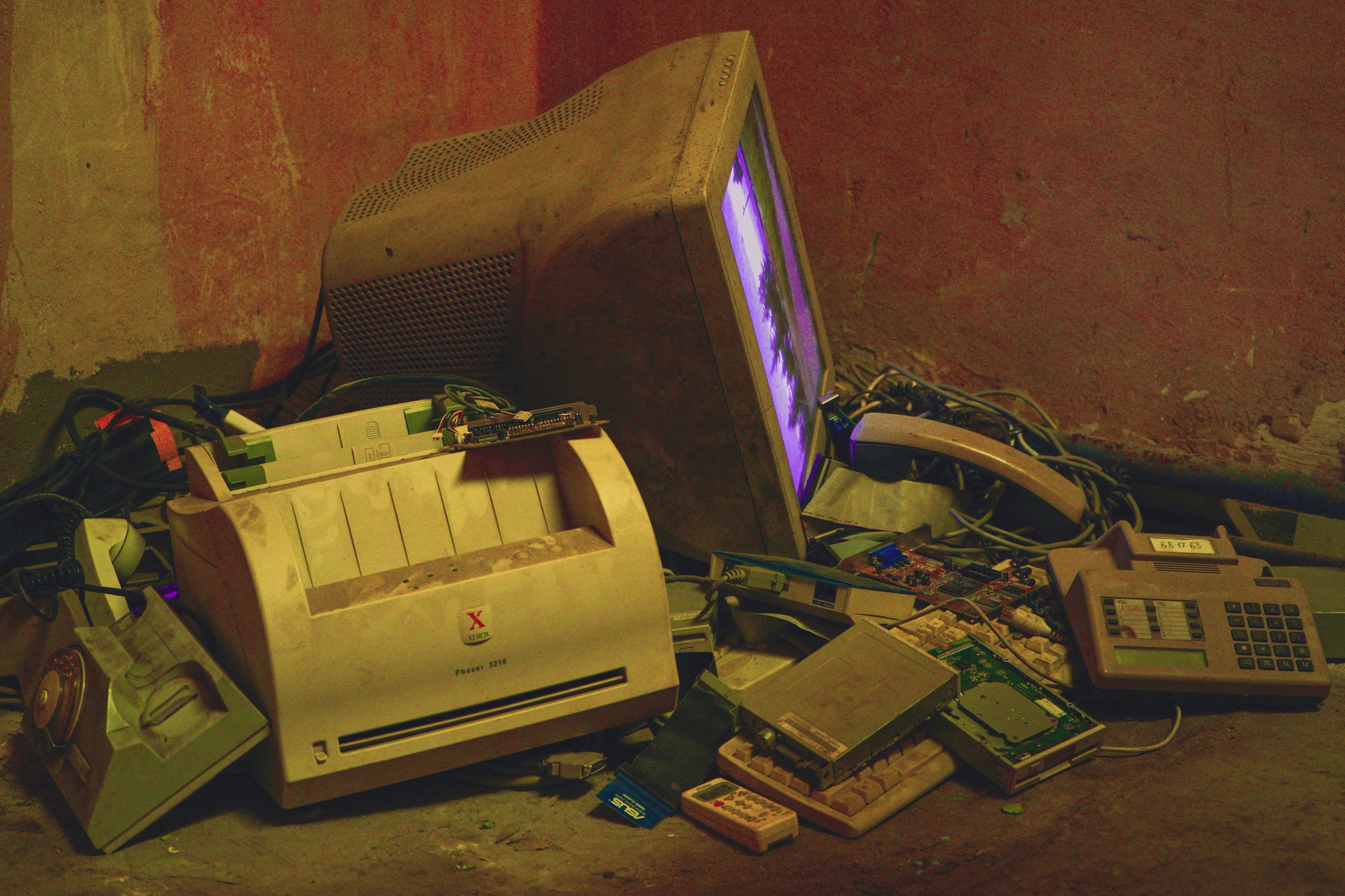Pile of old electronics including a vintage computer and printer left in a basement