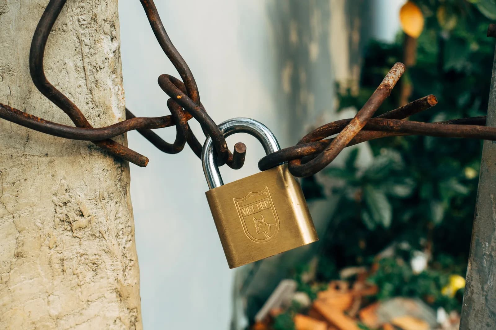 A brass padlock securing a wire on a concrete post, an image of privacy and on-device security