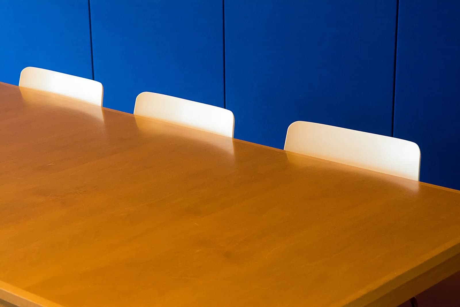 Clean modern meeting room with a wooden table against a blue wall, the kind of session a meeting recorder captures