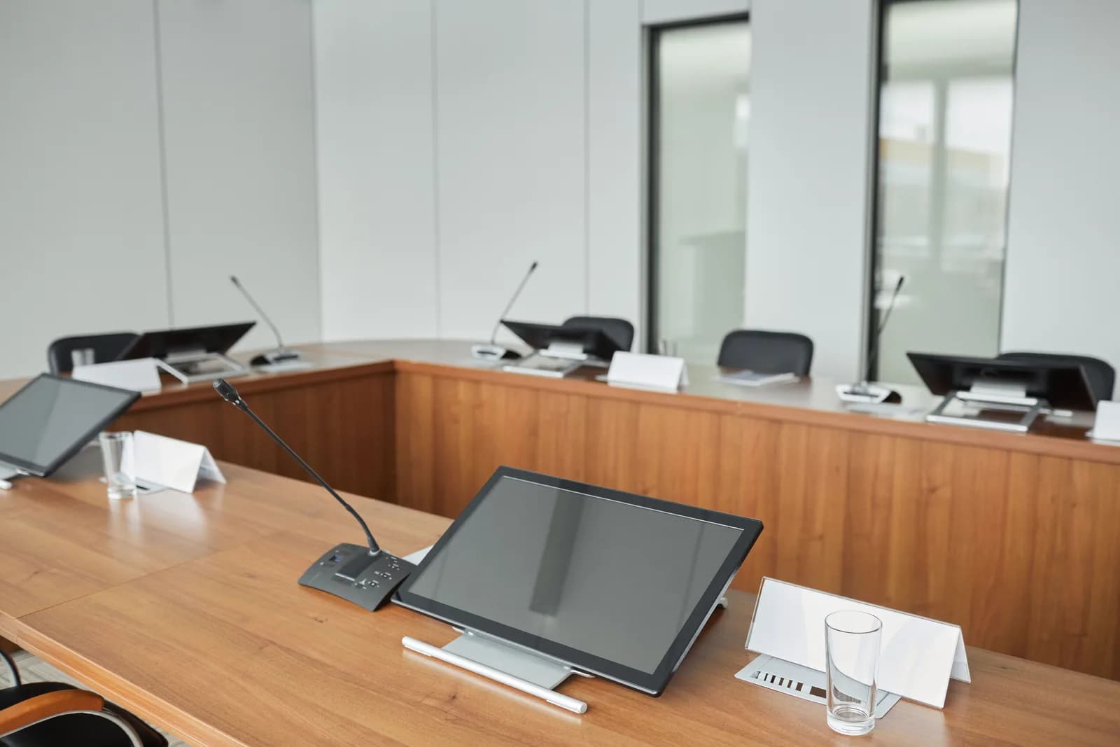 Conference table fitted with microphones and monitors, the kind of setup a meeting bot records