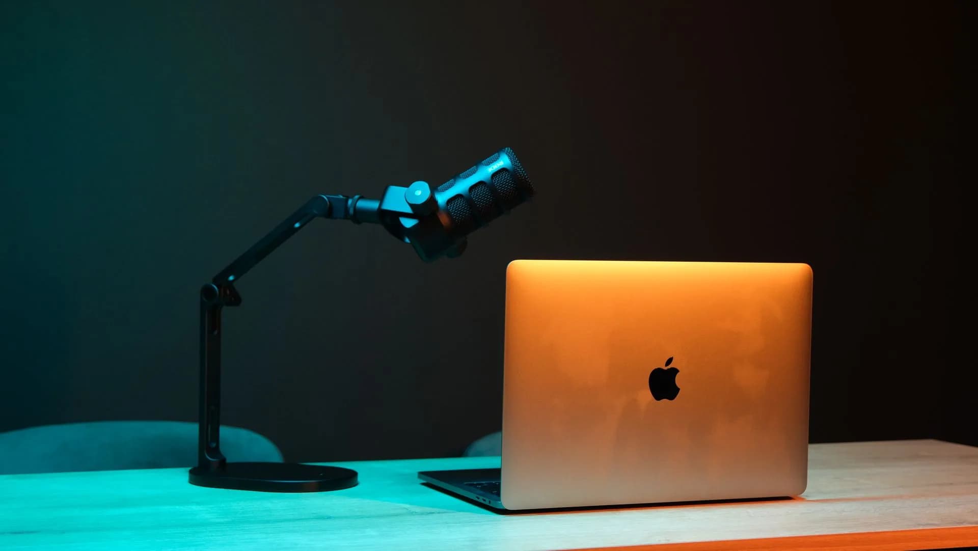 Microphone and laptop on a wooden desk under warm lighting, a dictation setup that works in any app