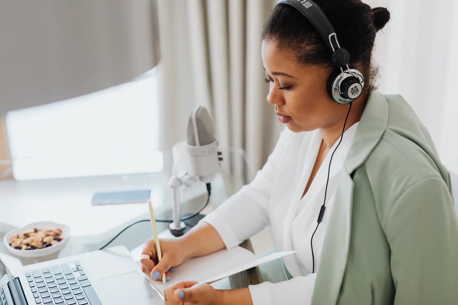 A laptop on a writing desk with a microphone, suggesting built-in voice dictation