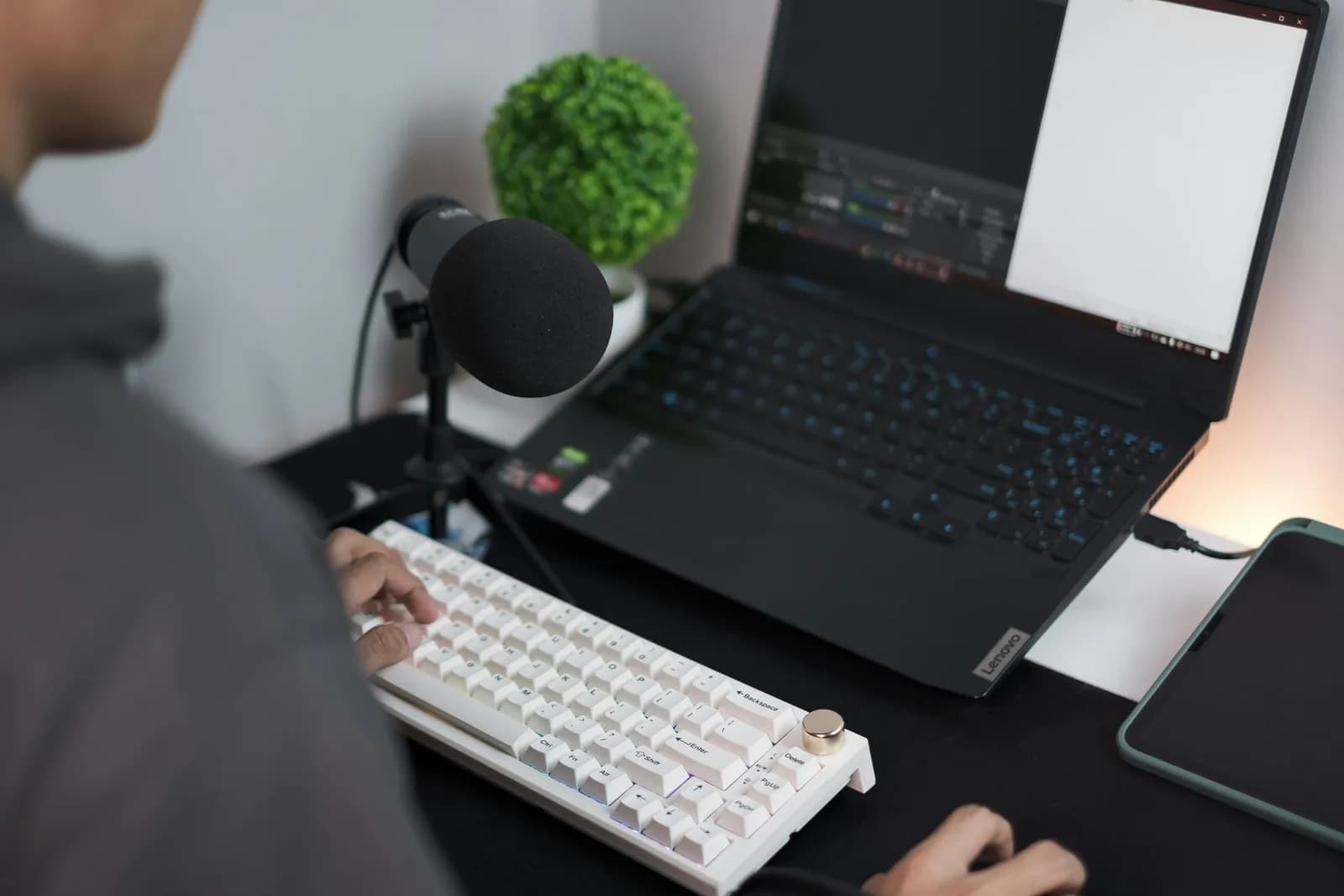 Person at a laptop on a quiet desk with a microphone nearby, evoking talking instead of typing