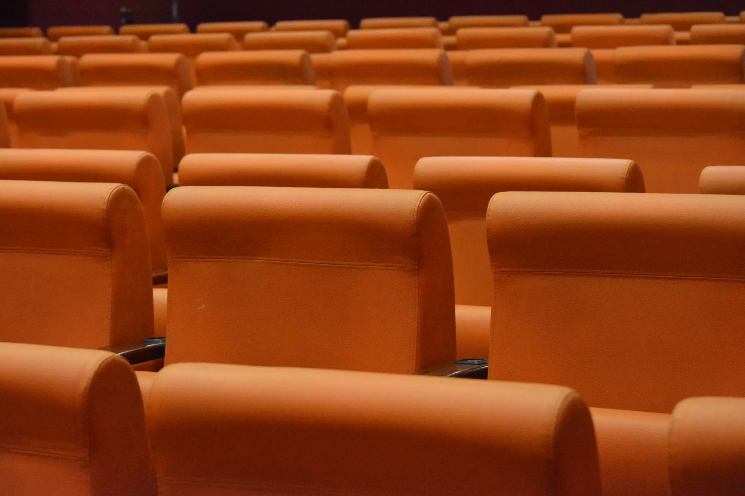 Rows of orange seats in an indoor auditorium, the setting where a lecture is captured live for transcription