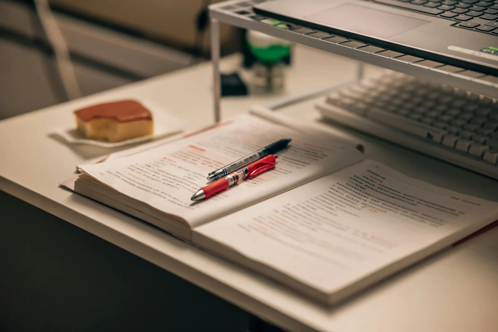 Notebook, pen, and an open laptop on a desk in a study setting, illustrating reviewing lecture material