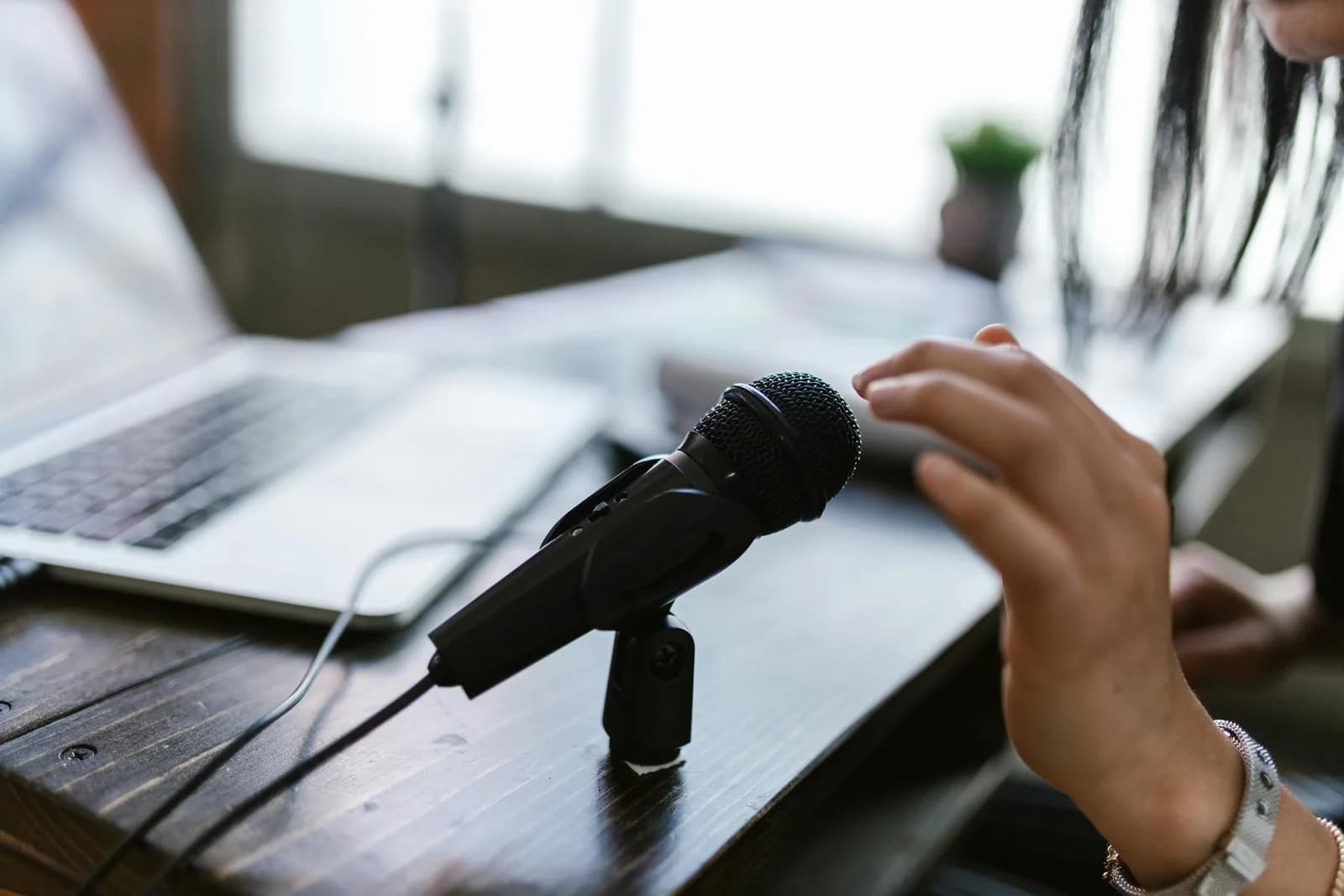 A Windows laptop open on a dark desk with a microphone nearby, suggesting voice typing on a PC