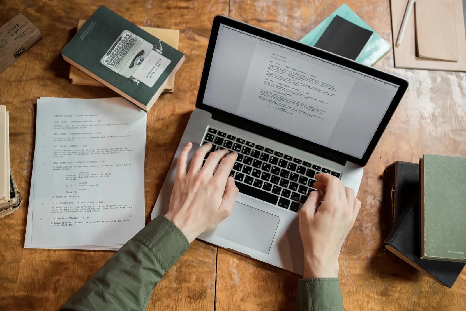 Writer's hands resting beside a keyboard and an open document on a dark desk, evoking drafting by voice