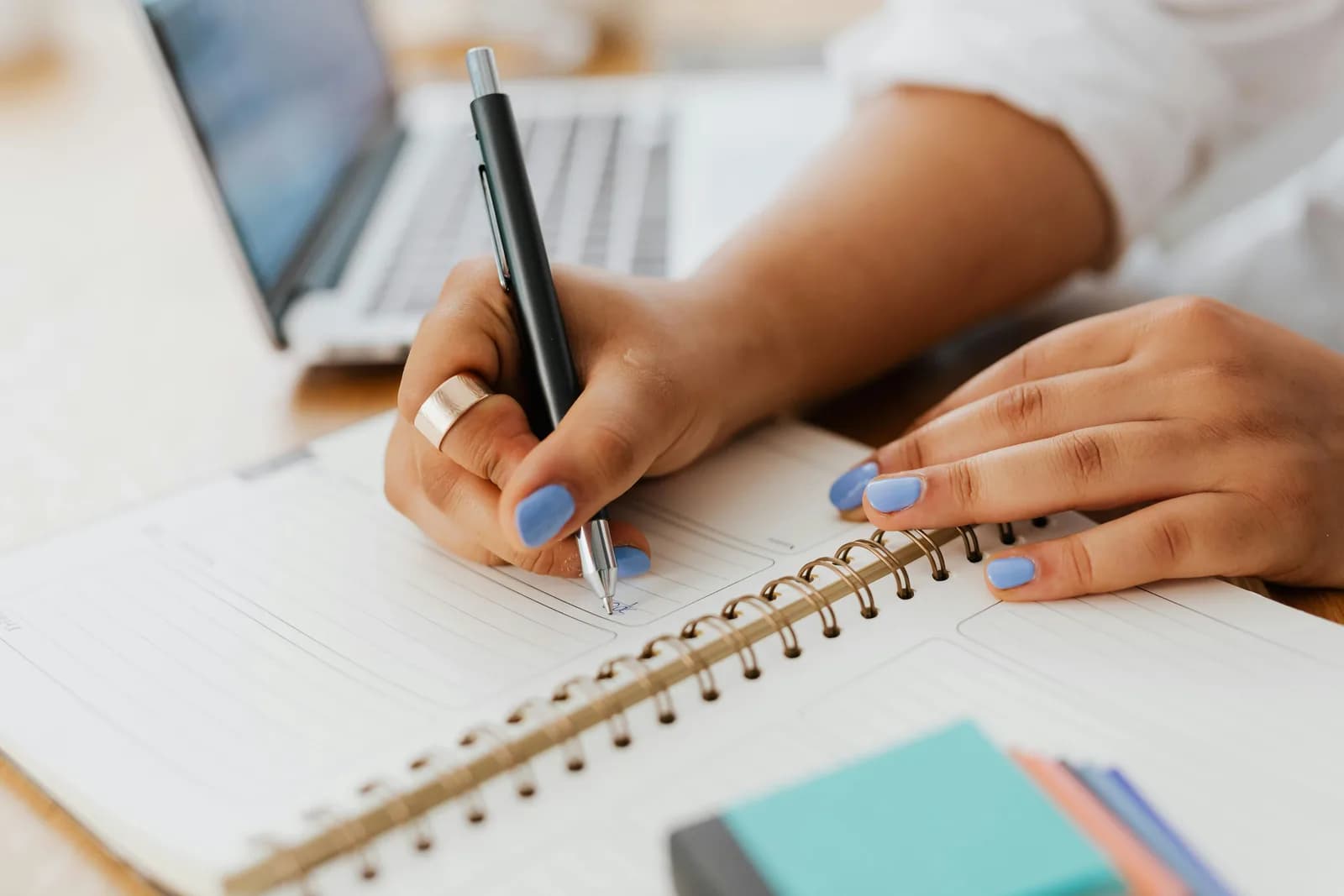 A writer typing at a laptop with a notebook nearby, illustrating the drafting flow voice replaces