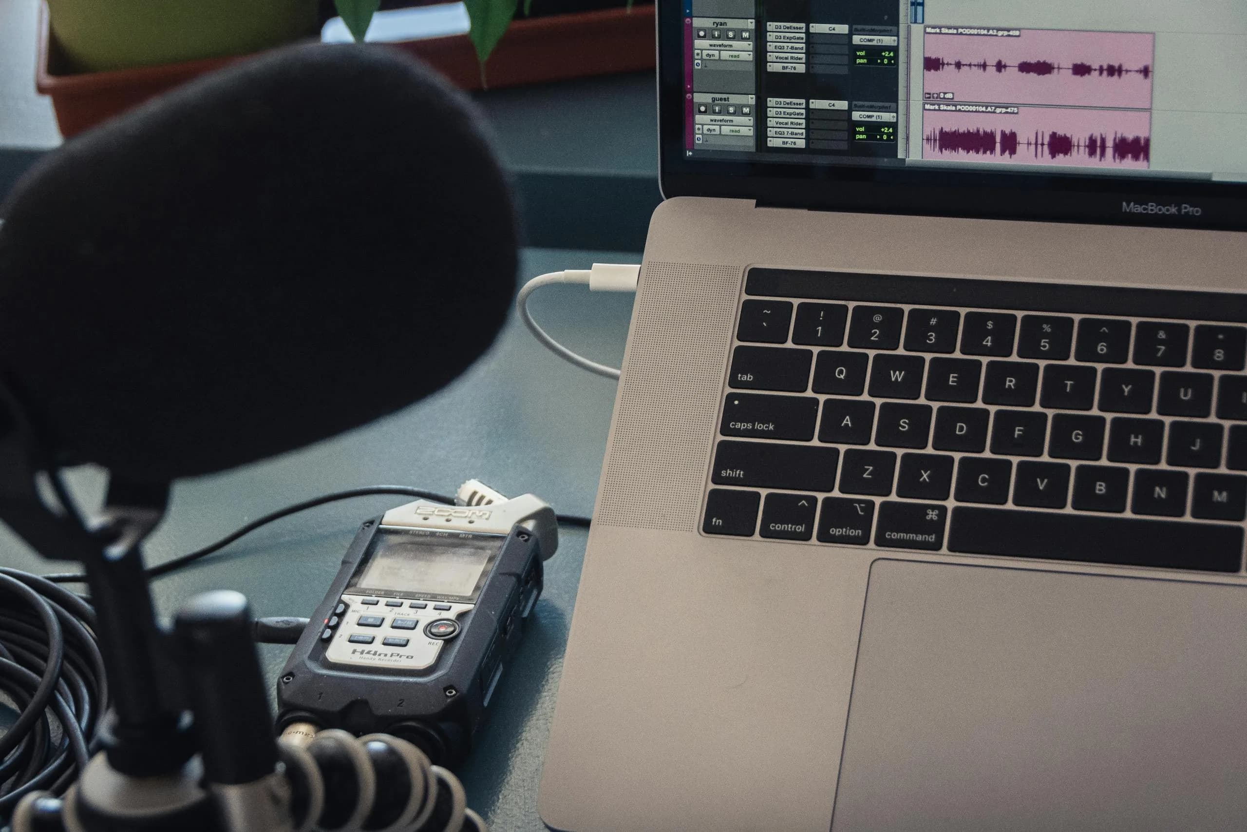 Microphone and laptop on a studio desk, the recording-and-transcription scene behind every Rev alternative