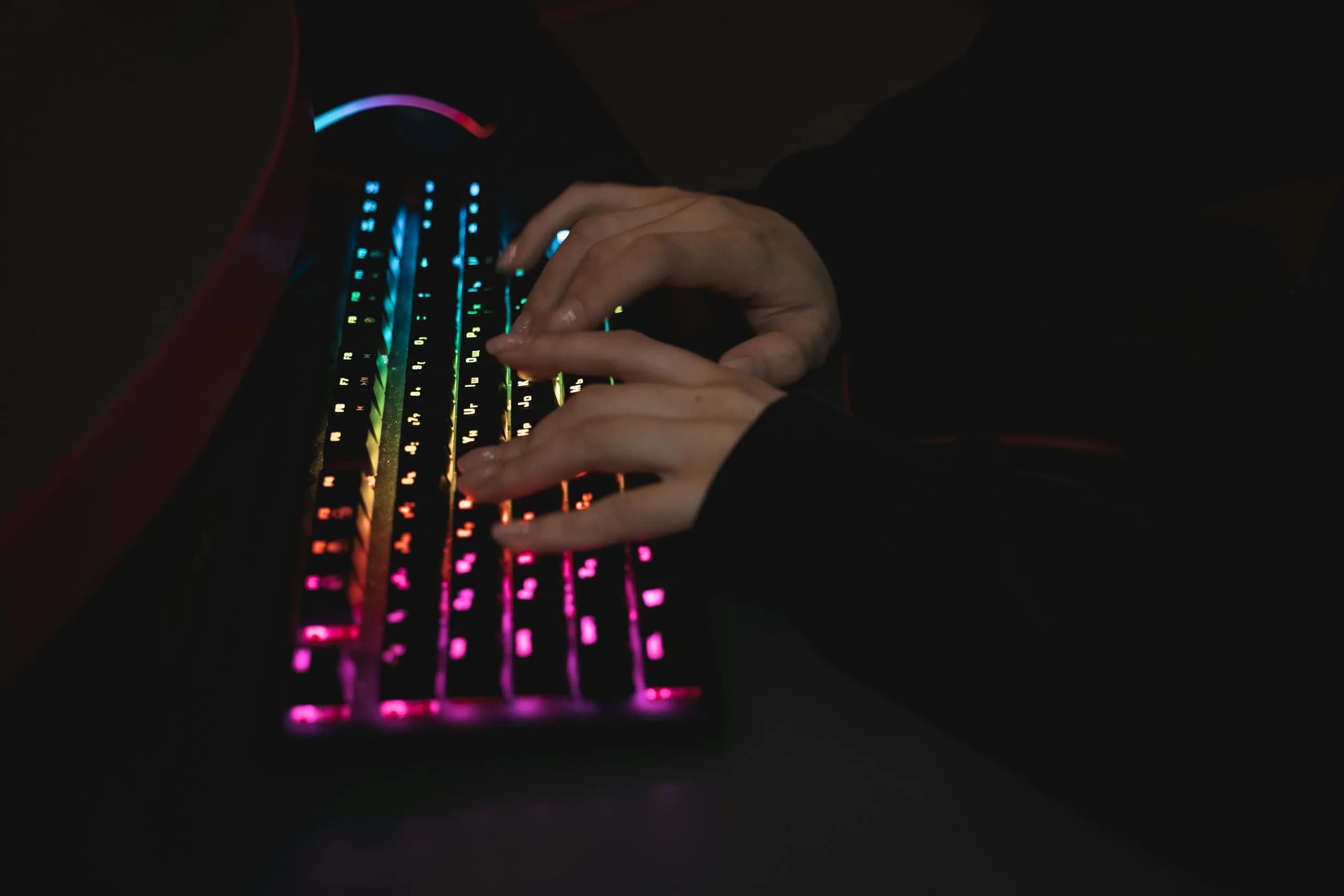 Hands on a backlit mechanical keyboard, the live-dictation path that skips the upload step entirely