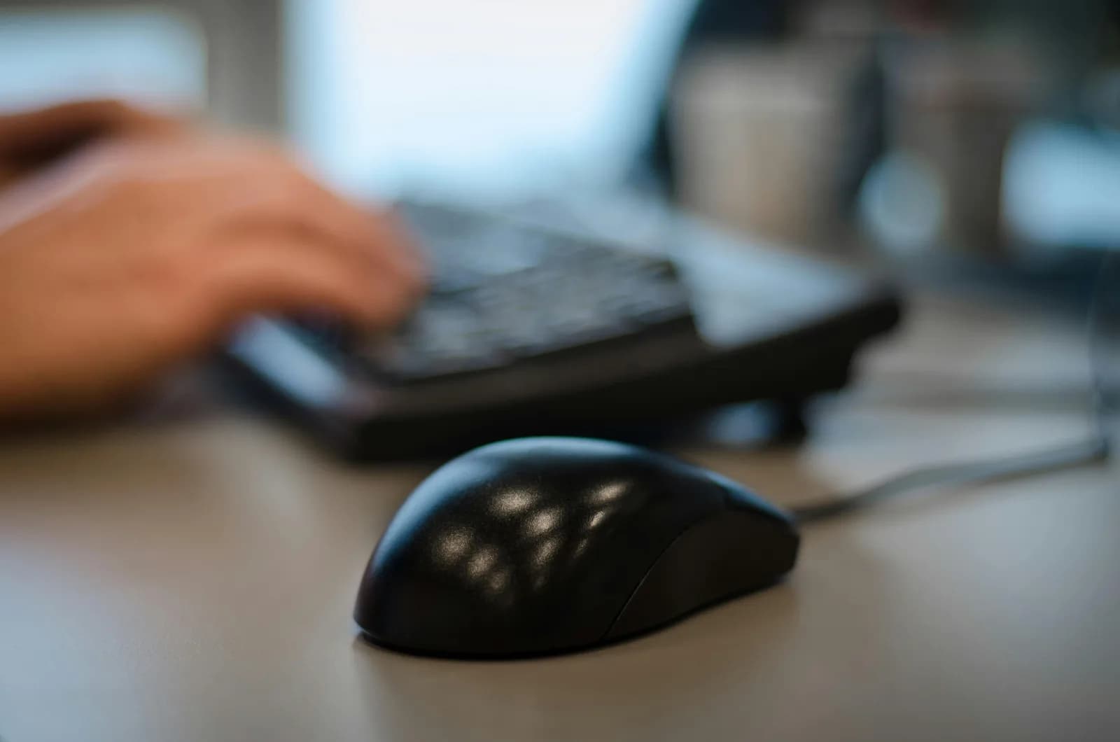 Computer mouse in focus on an office desk with a blurred background, suggesting workflow friction