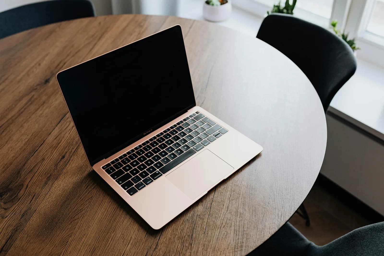 MacBook open on a wooden desk in soft light, representing macOS dictation