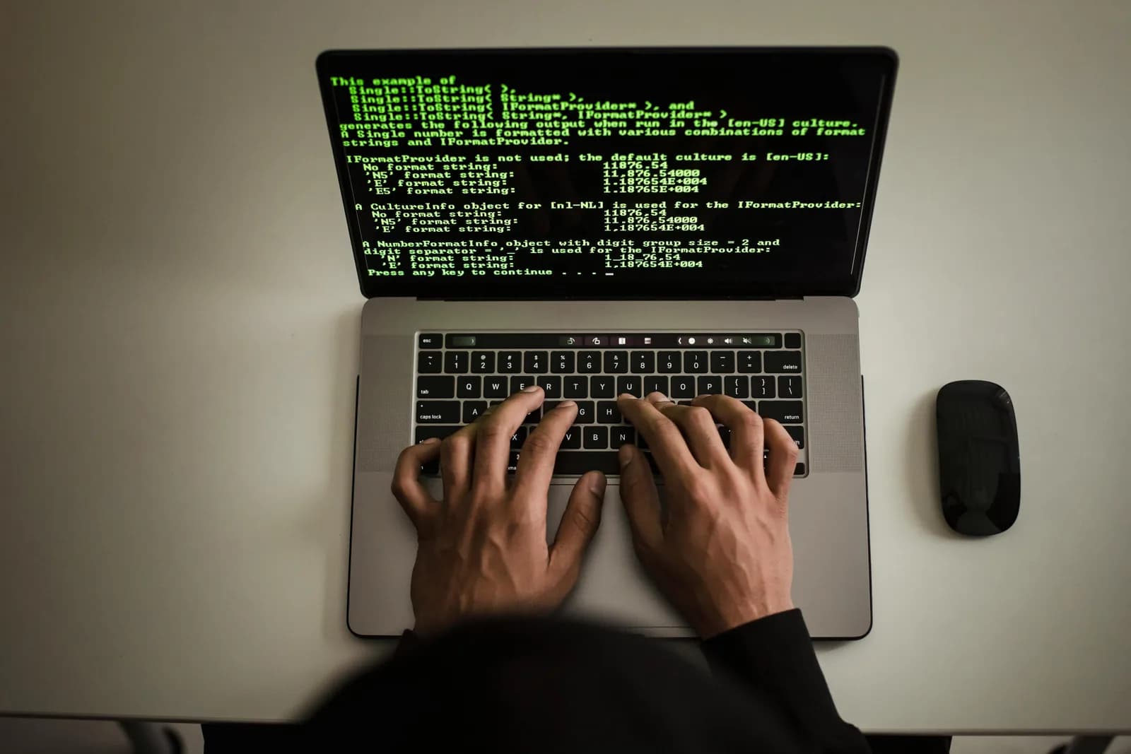 A developer's hands resting away from a keyboard while code fills the screen, suggesting hands-free coding