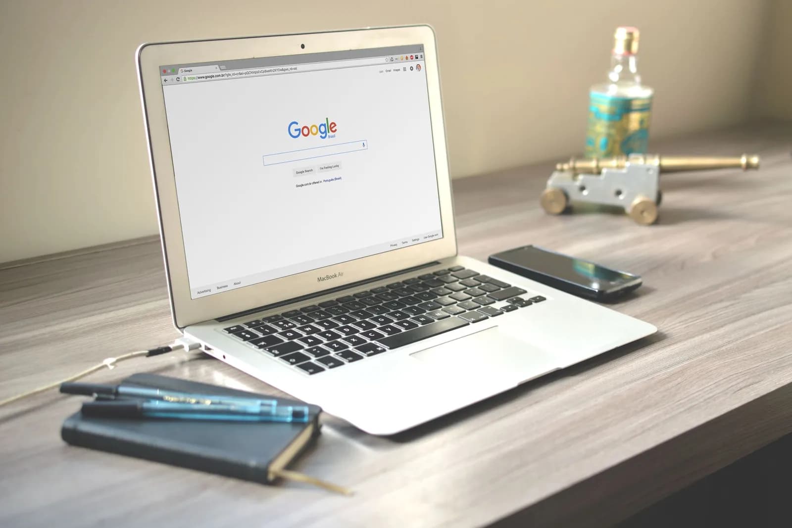 A laptop displaying a search page beside a notebook on a wooden desk, evoking dictation that works across the whole desktop, not just the browser