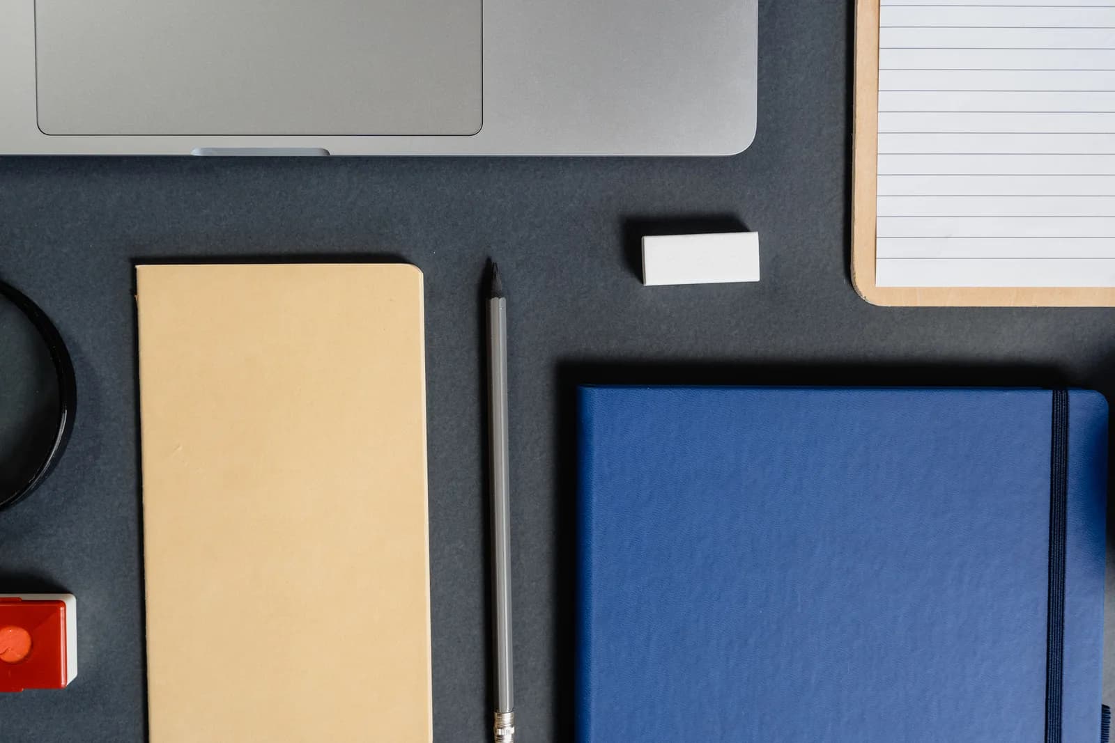 Laptop on a dark desk beside a coffee cup and notebook, evoking organised data entry and dictation