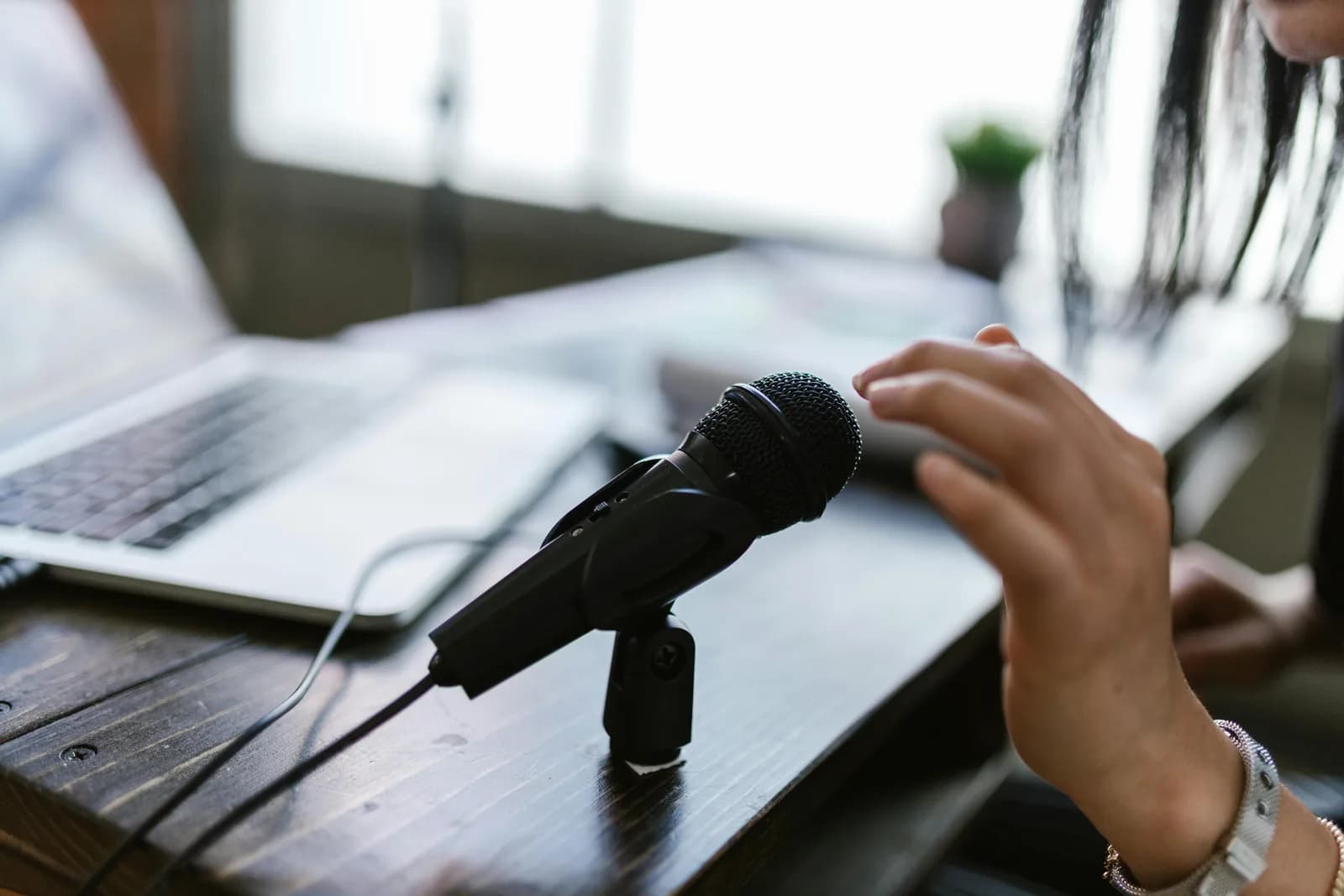 A calm, tidy desk with a microphone and laptop, no keyboard in use, suggesting writing by voice