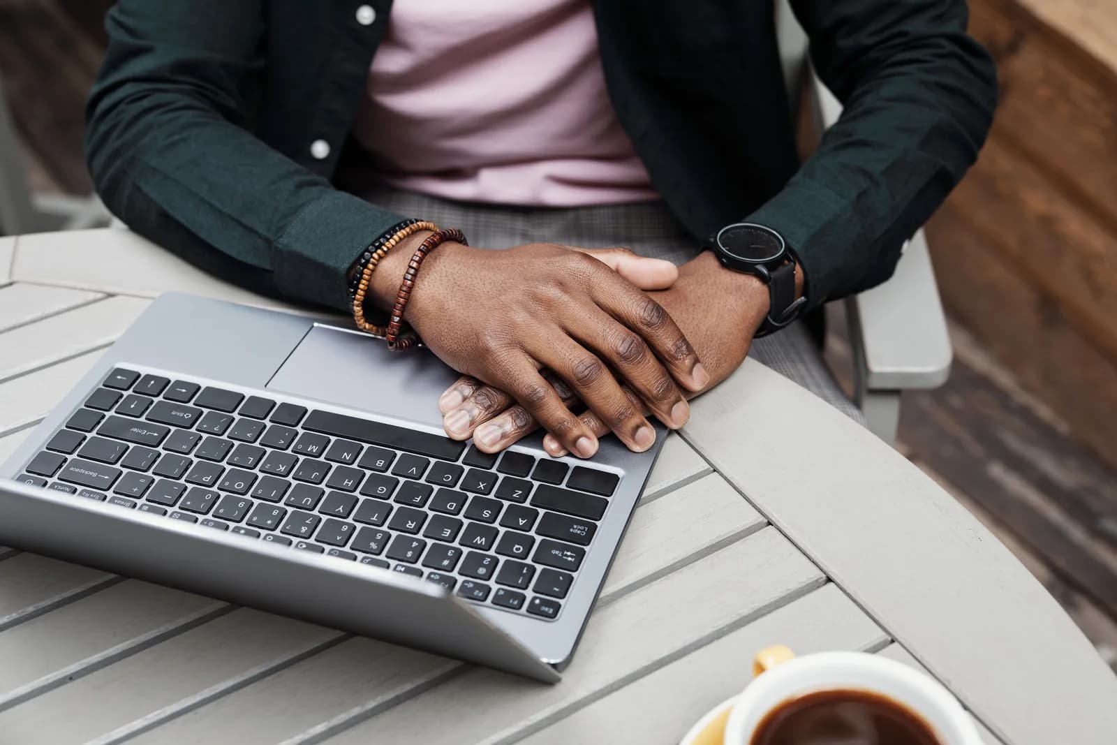 Hands resting calmly beside a closed laptop, suggesting a break from typing