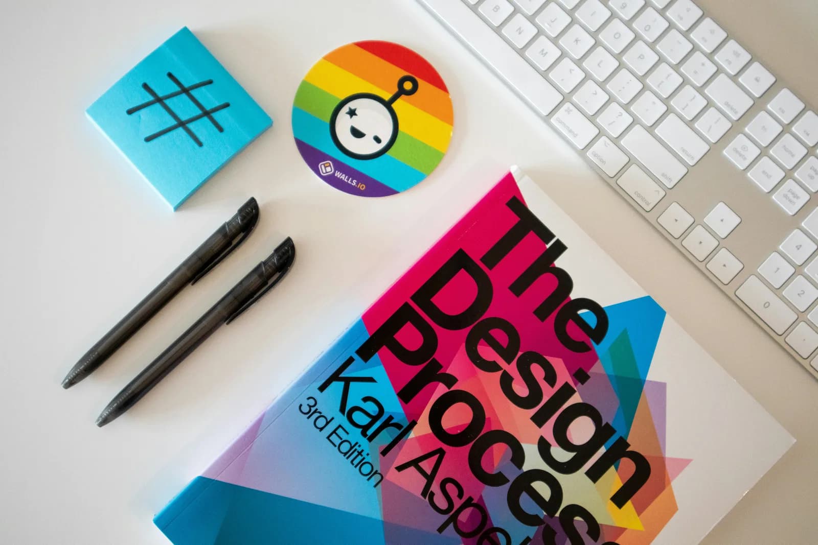 Flat-lay creative desk with a design book, pens and colorful stickers for layout work
