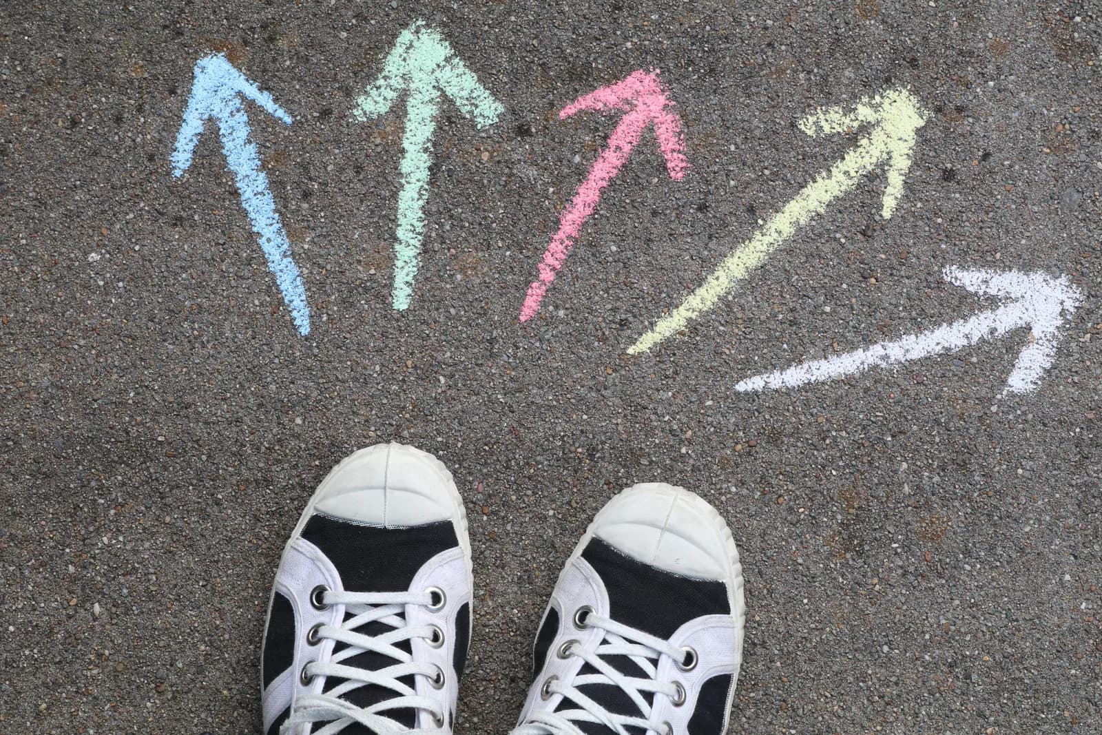 Two arrows chalked on pavement pointing different directions, illustrating a tool choice