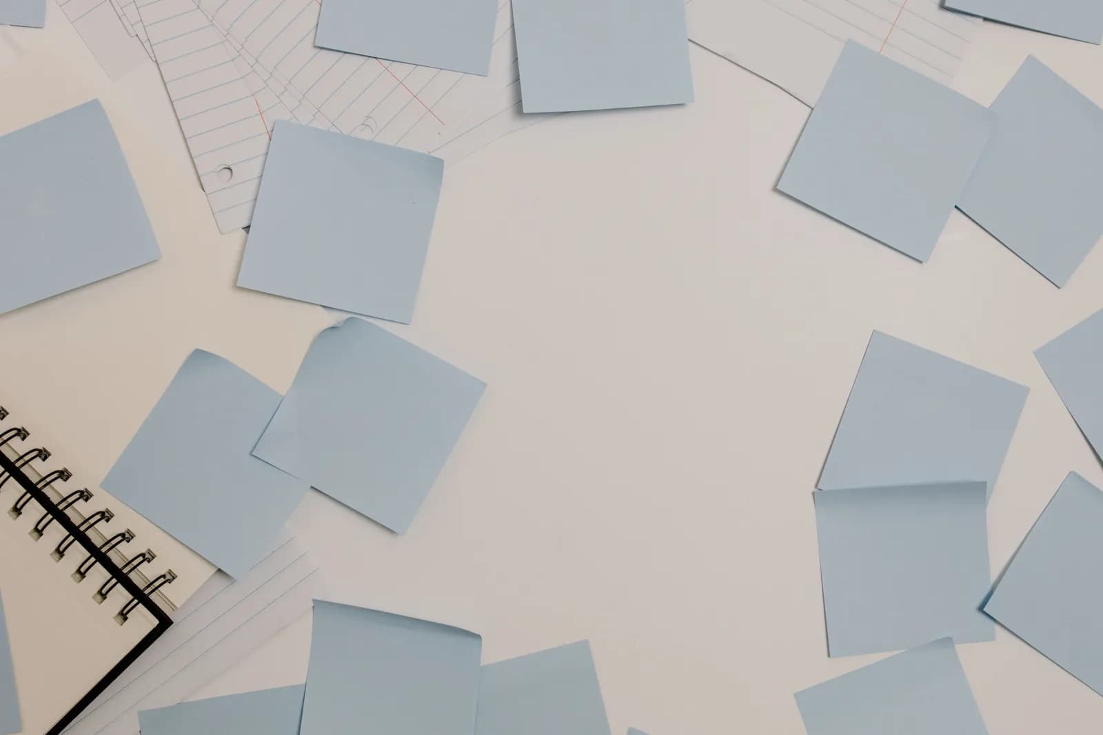 Top view of a desk with blue sticky notes, a spiral notepad, and lined paper for quick reminders