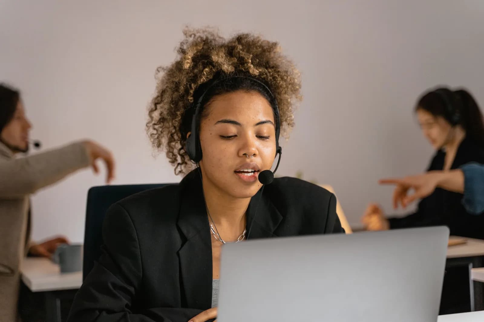 Sales rep at a desk speaking while a CRM dashboard glows on the laptop screen, evoking dictation into a record