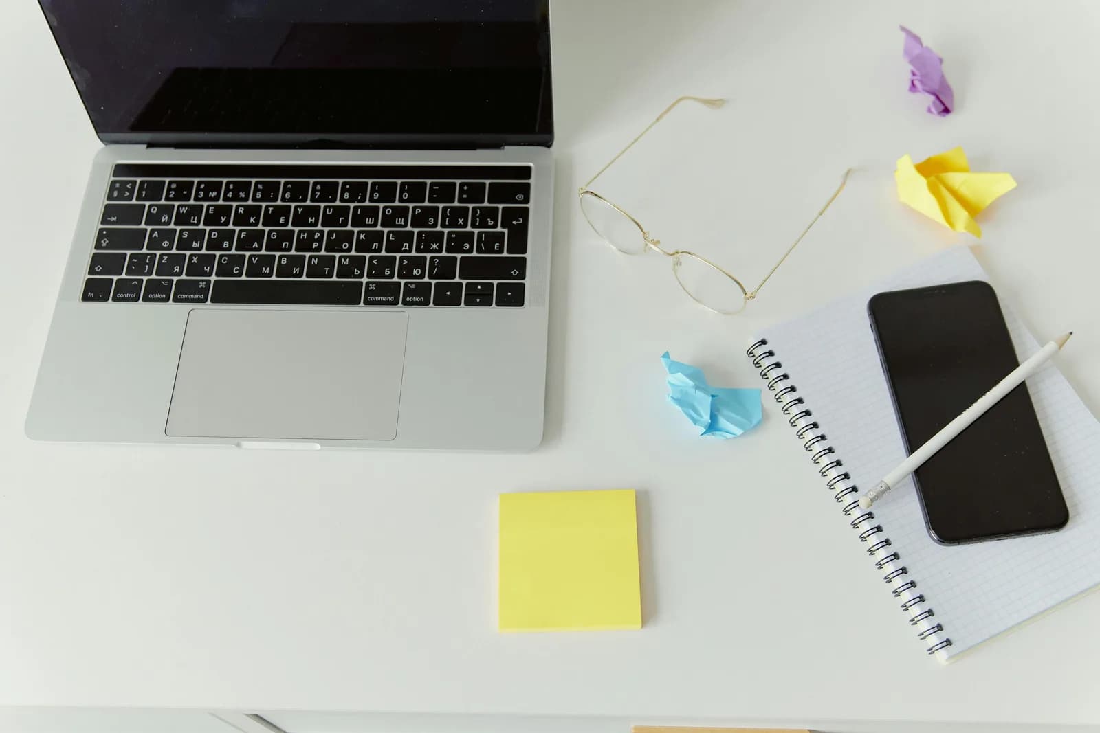 Minimalist desk with a laptop and notepad, illustrating manual note-taking in a CRM workflow