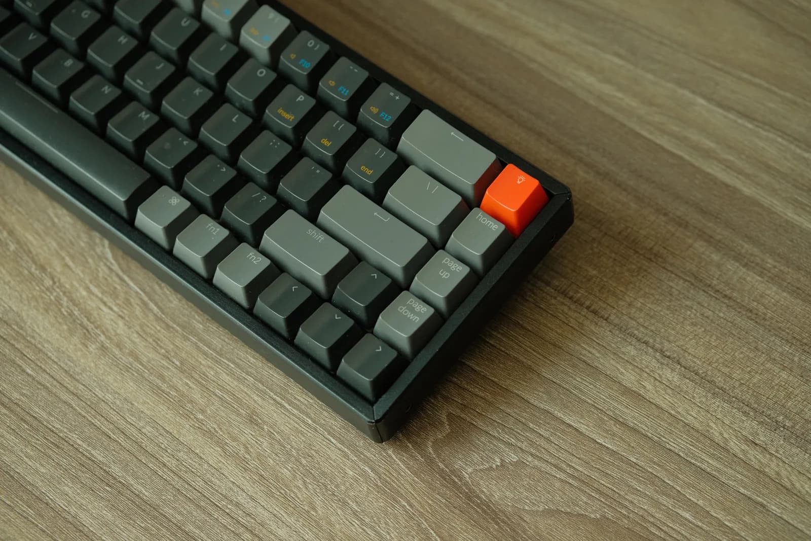 Mechanical keyboard with an orange accent key on a wooden table