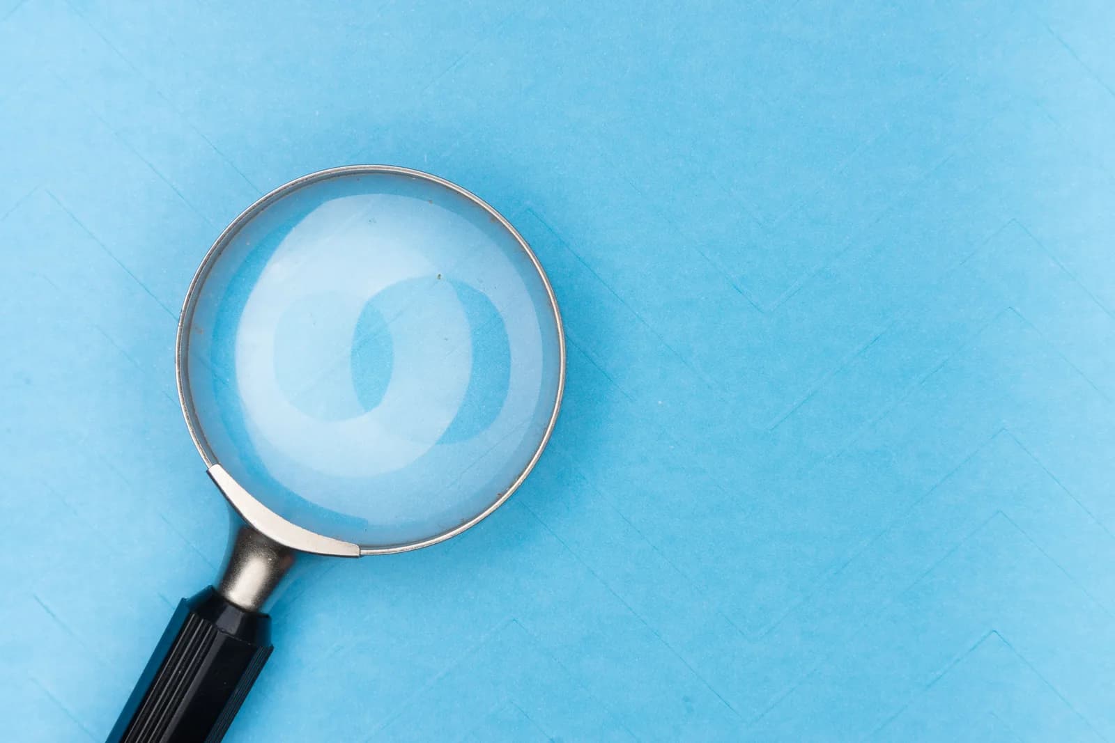 Magnifying glass on a blue surface, evoking the hunt for what is breaking transcription