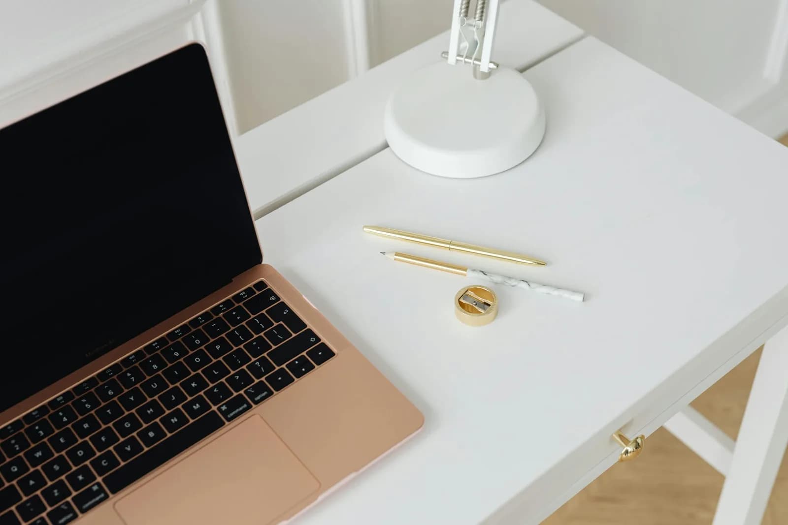 A clean, minimalist desk with a laptop and lamp, evoking voice dictation tools