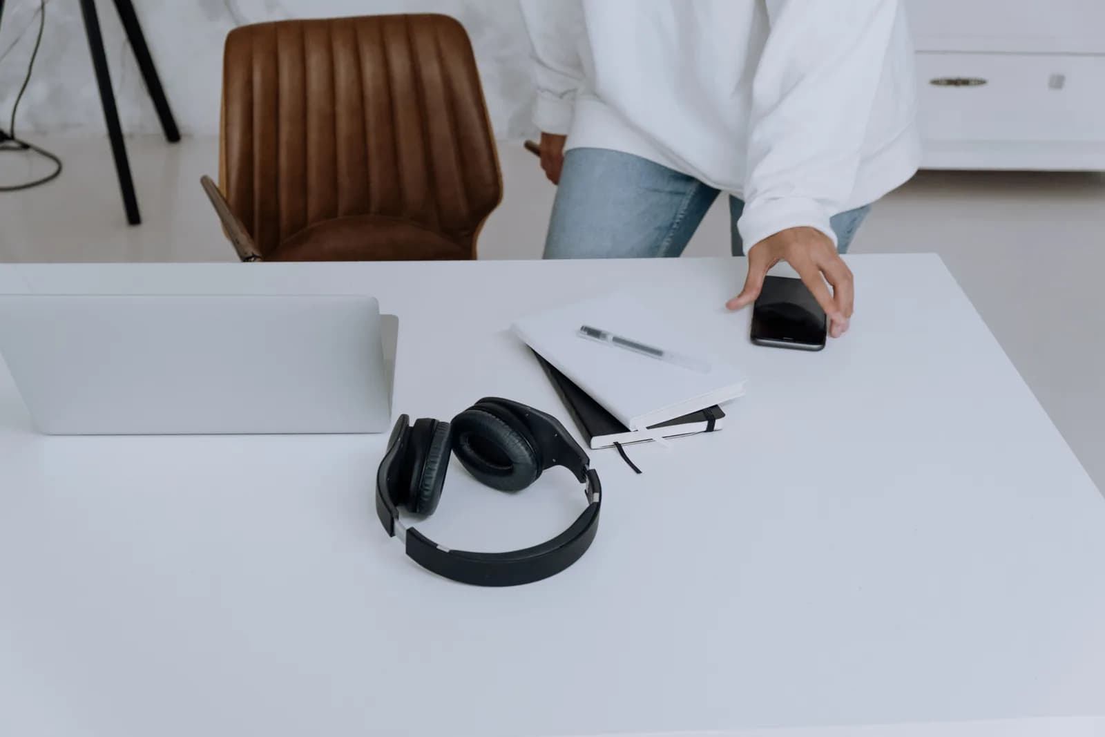 Clean home office desk with a laptop, headphones and a notebook, set up for reviewing a Zoom meeting transcript