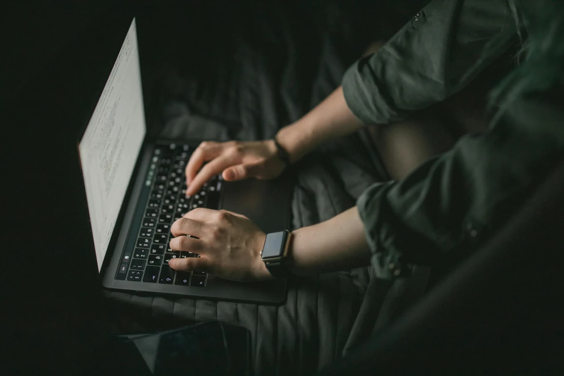 Hands typing on a laptop keyboard in a dim room after voice typing stopped working