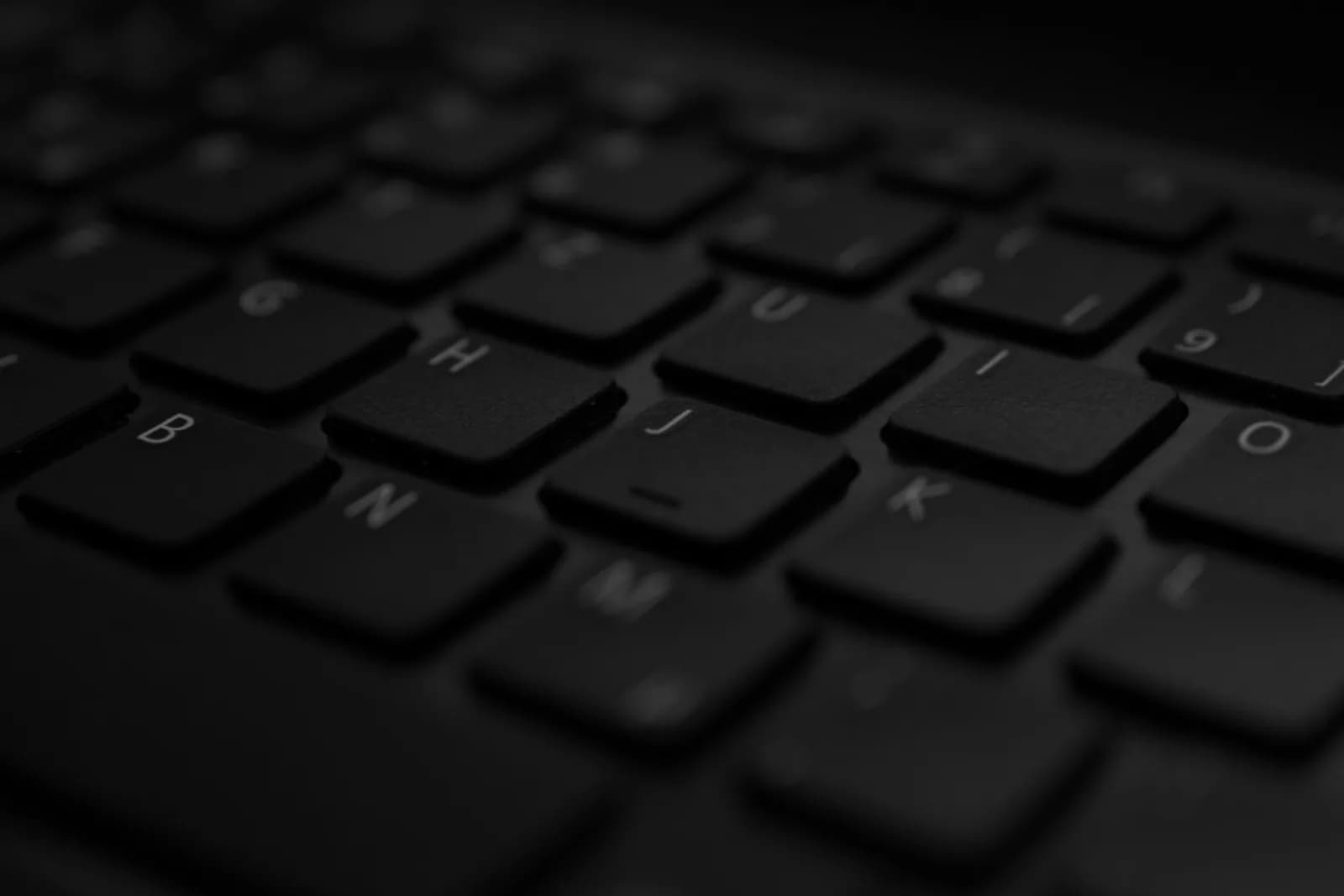 Close-up of a black laptop keyboard with soft lighting on the letter keys