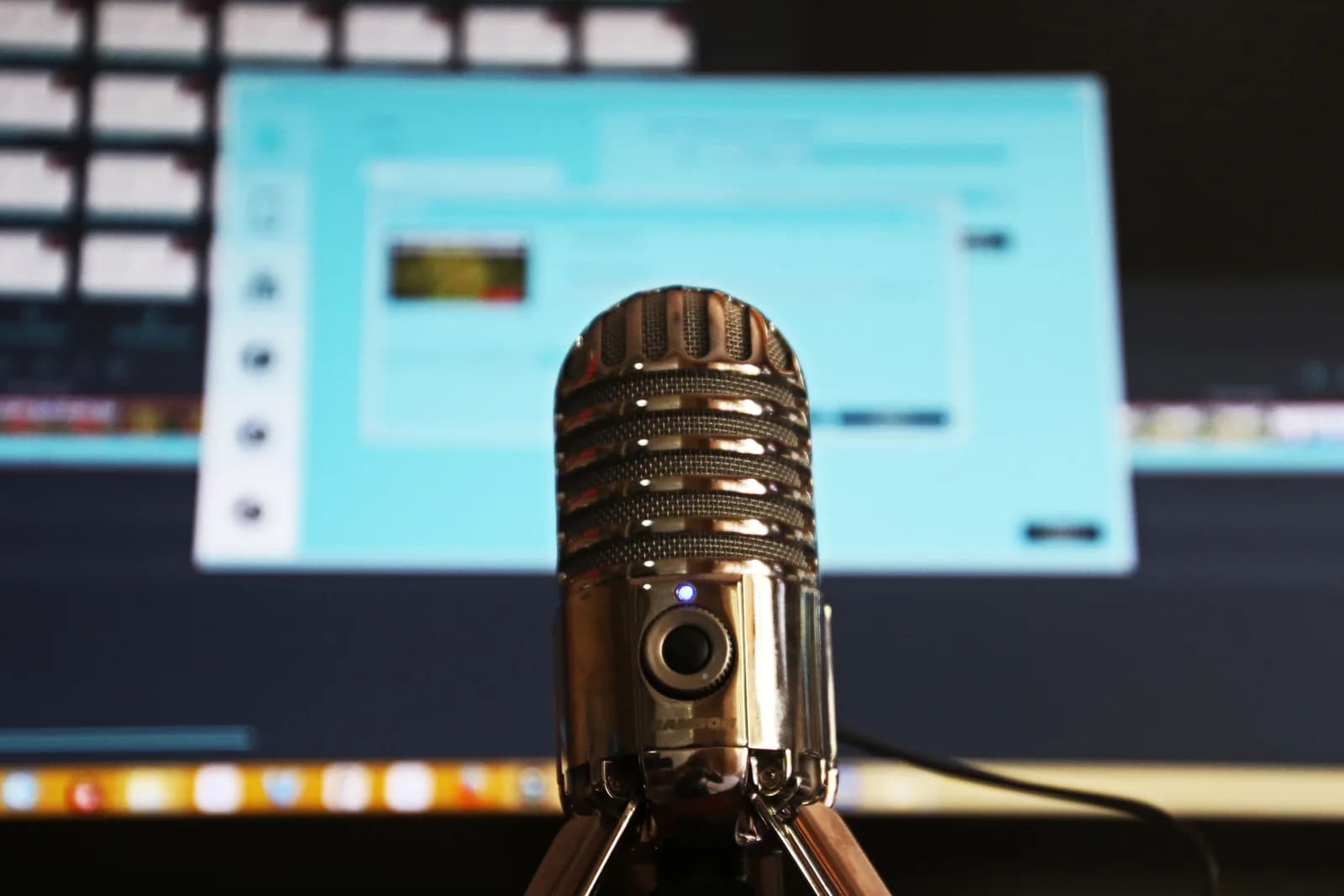 Condenser microphone in focus with a blurred computer screen behind it