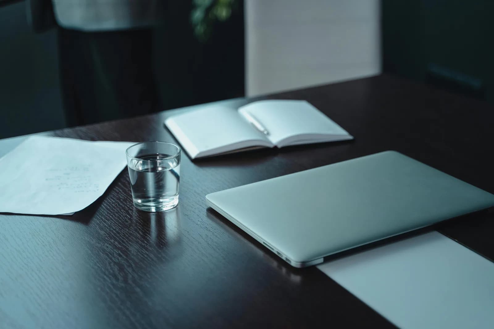 Notebook, pen, and open laptop on a desk, illustrating drafting work between client meetings