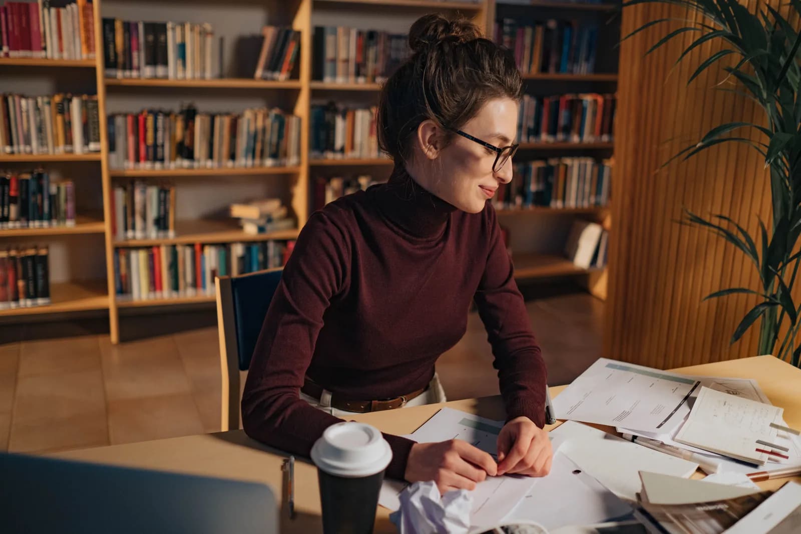 Student in a library writing notes, illustrating coursework and study by voice