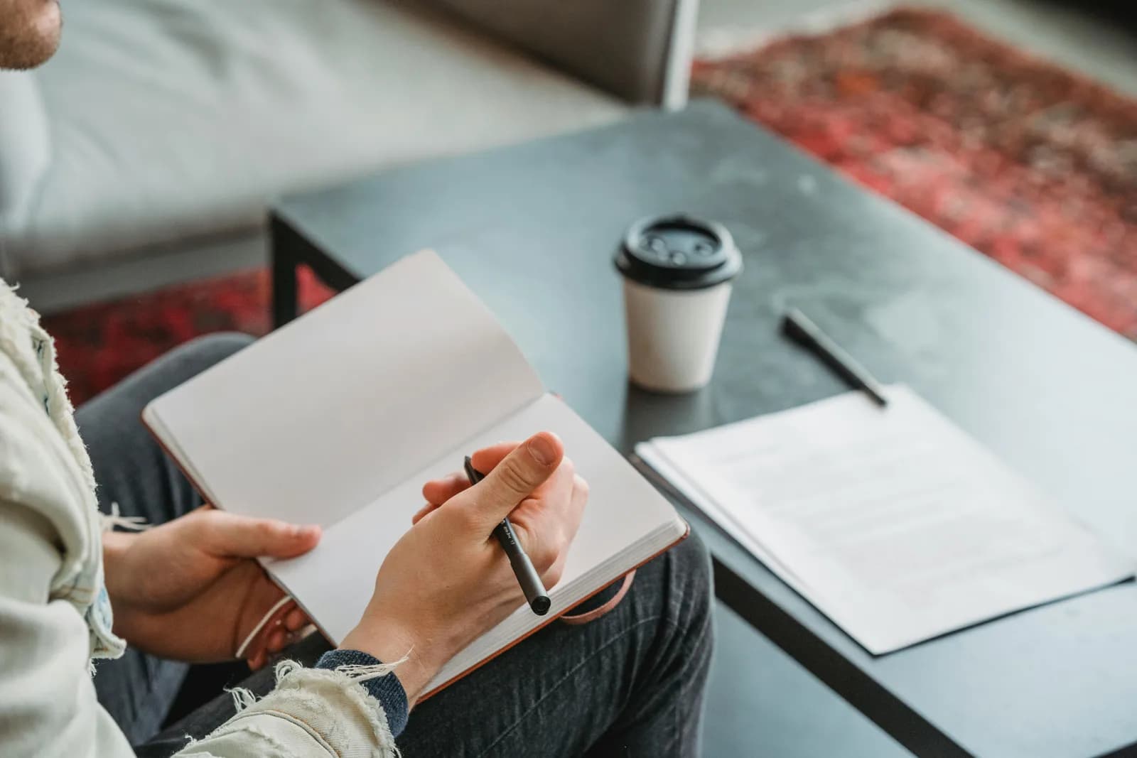 A writer's hands resting near a notebook and keyboard, pausing between sentences