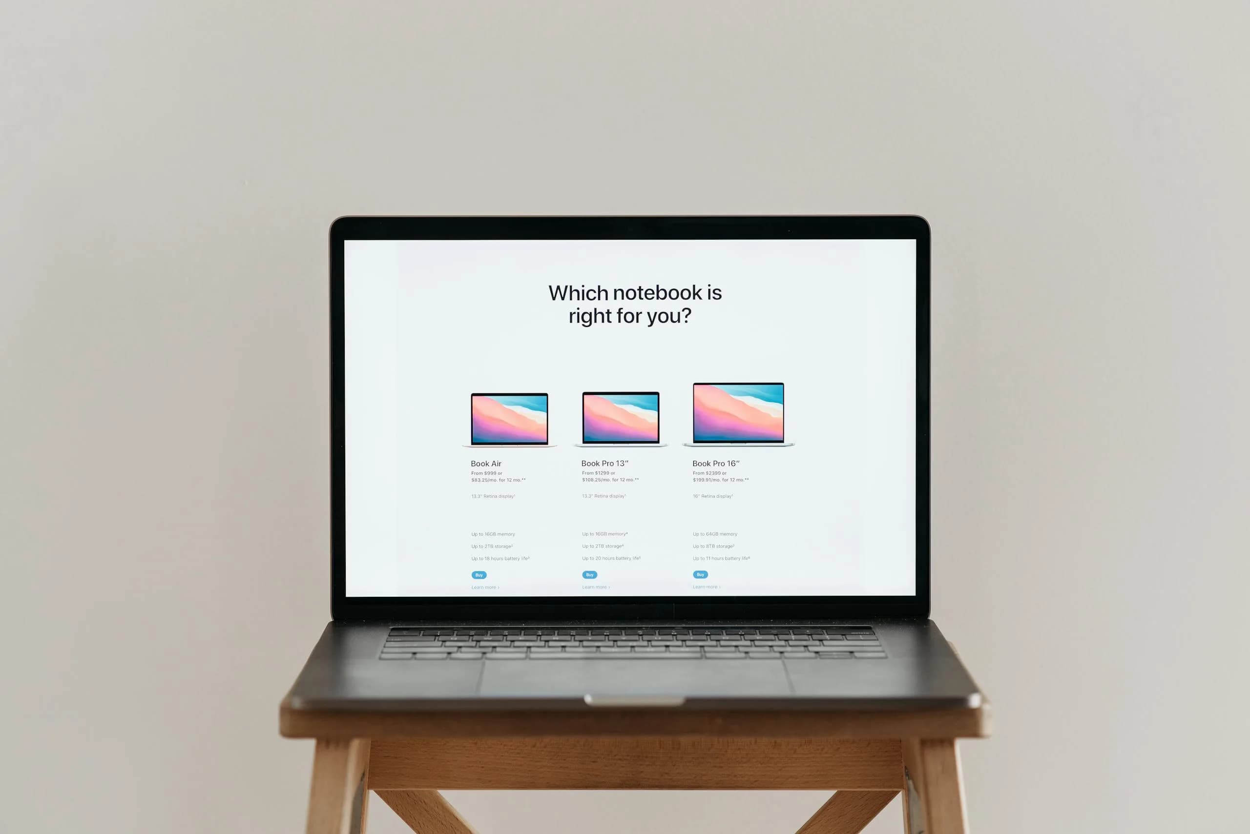 Open laptop on a wooden stool displaying a notebook-style comparison chart, evoking a tools roundup