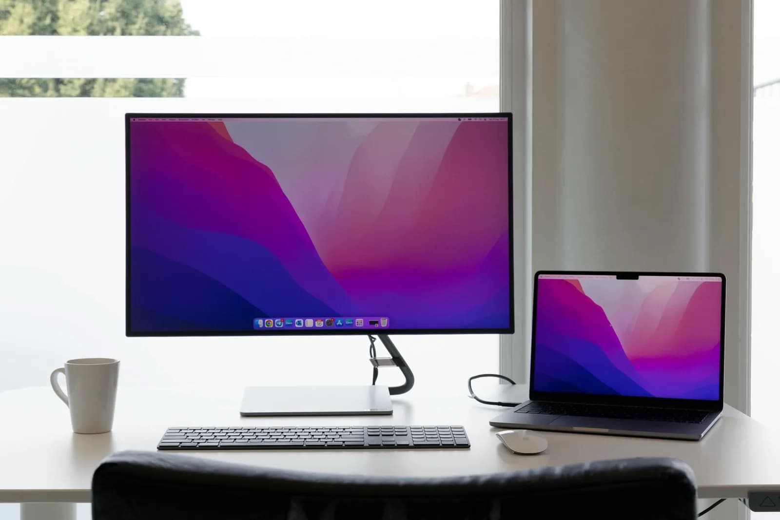 Minimalist desk with dual monitors, a laptop and keyboard on a clean surface for editing text