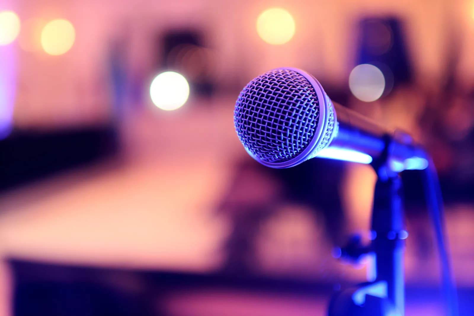 A microphone on a stand in front of a blurred lecture setting, representing recorded-audio transcription