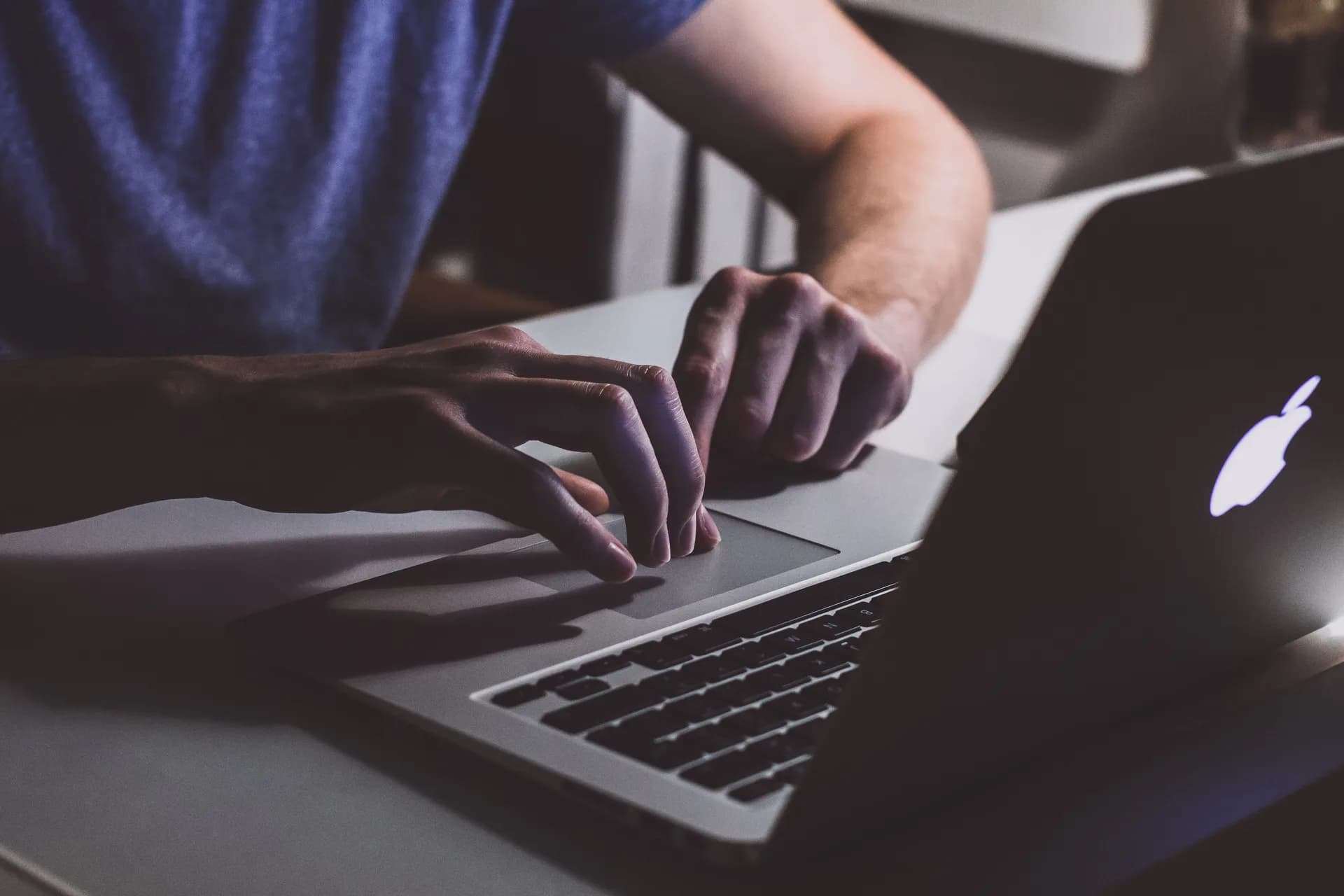 Hands resting on an open laptop keyboard in a dim office, evoking troubleshooting a stalled dictation feature