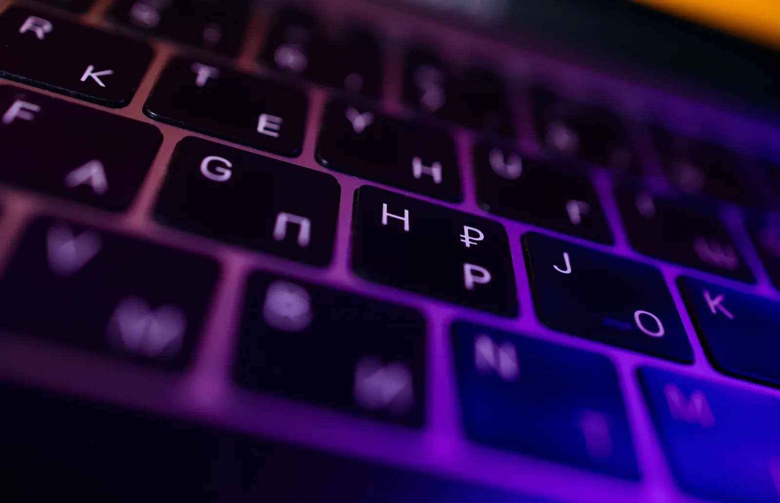 Close-up of a keyboard with Cyrillic letters under purple light, evoking language settings