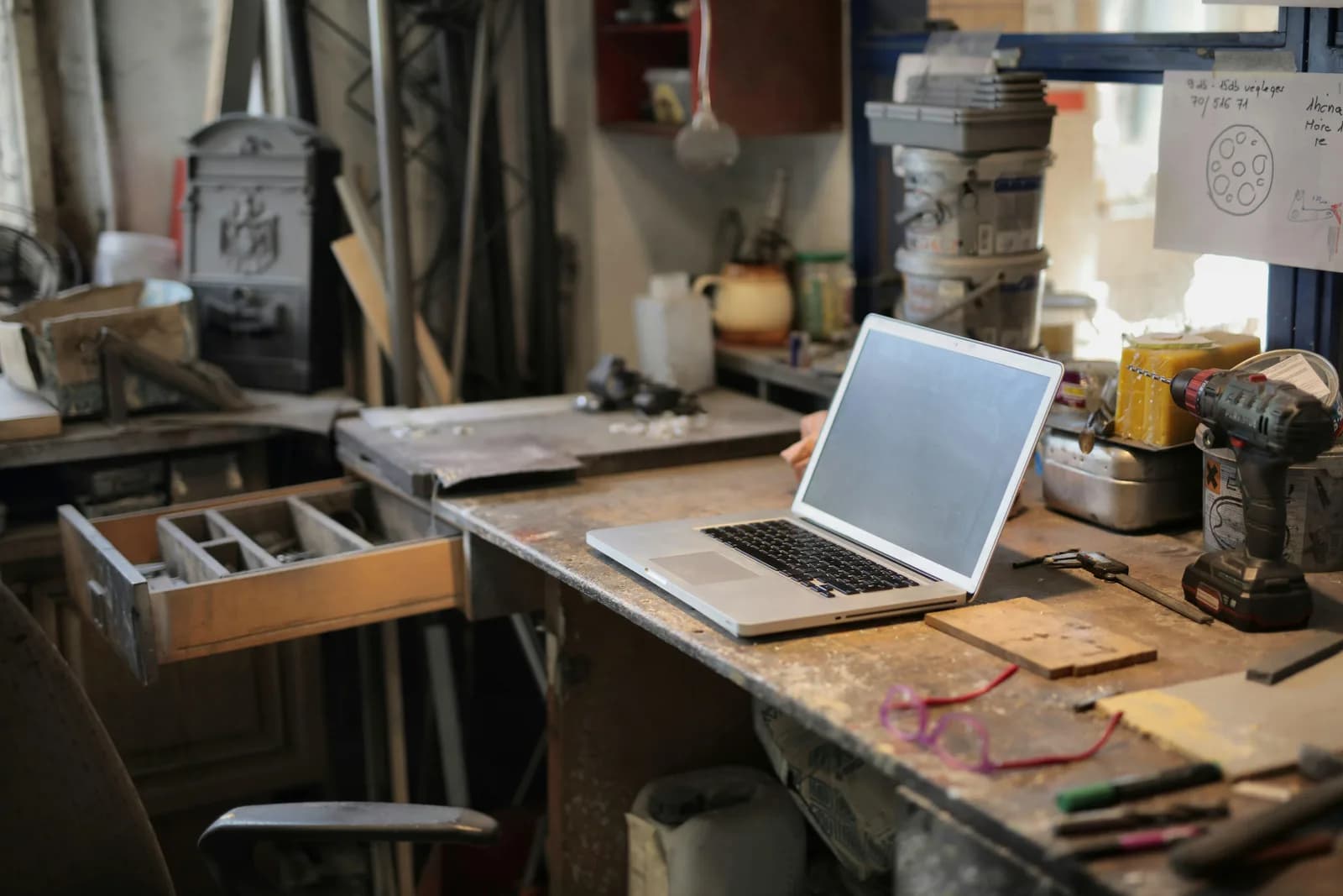A laptop surrounded by hand tools on a dark background, representing a reset and rebuild