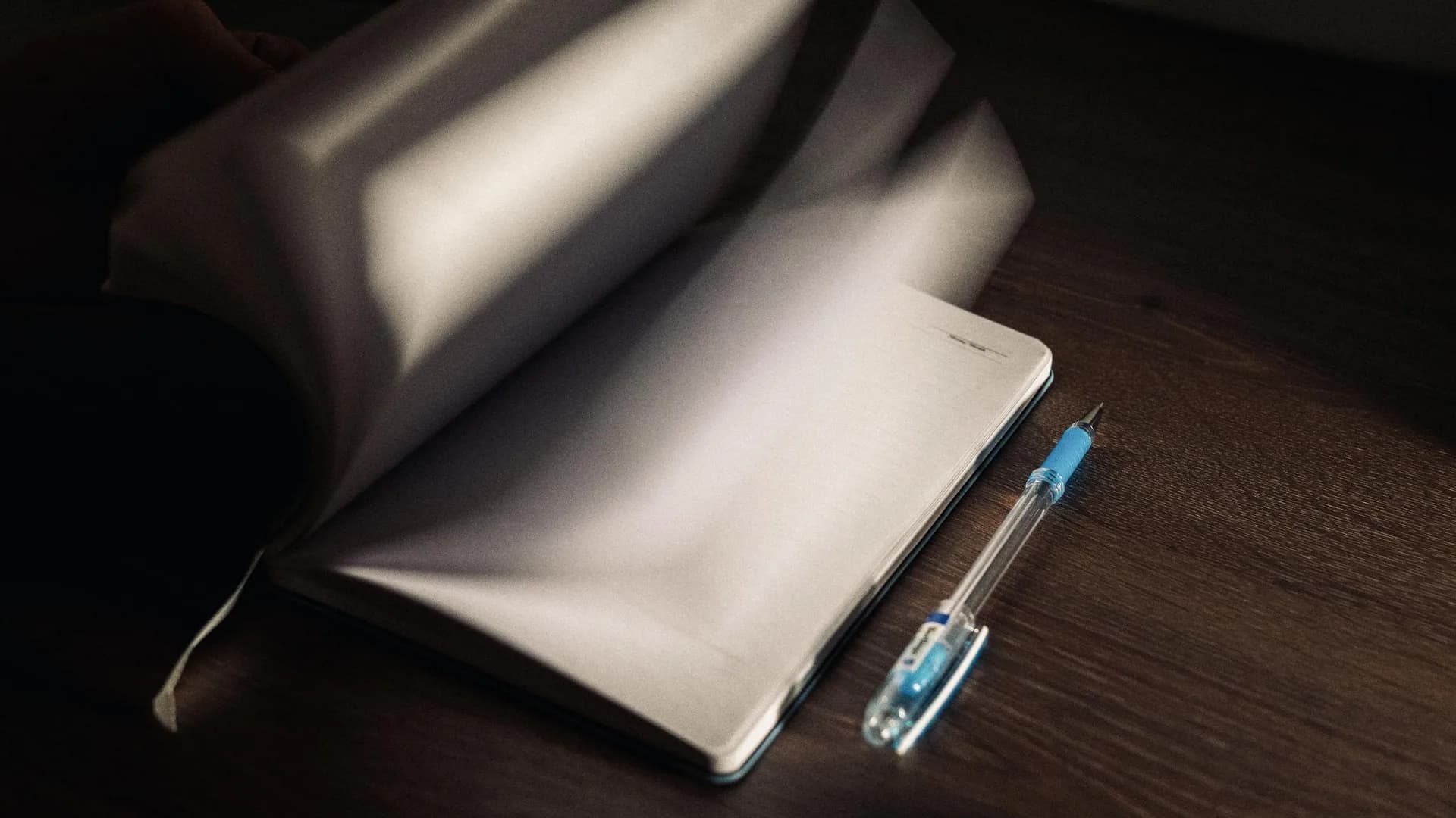 A blinking cursor on a blank screen at a cluttered desk, the moment before anyone starts writing